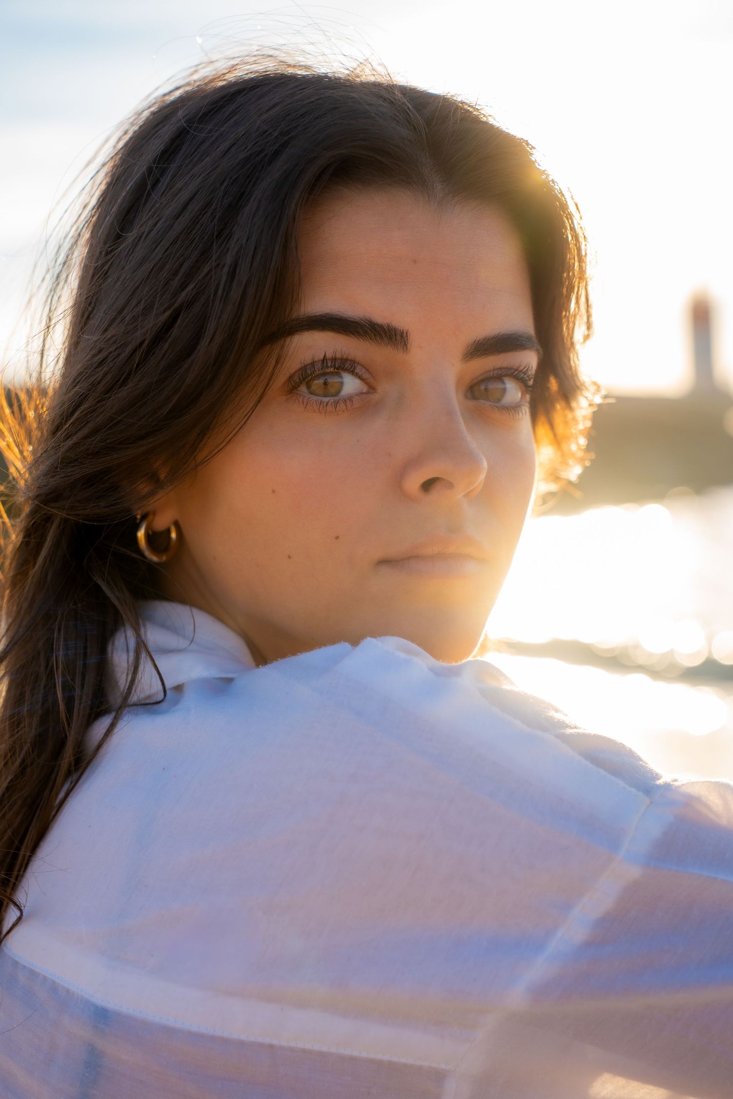 Portrait of a woman on the beach in warm natural light, with ocean and soft tones creating a cinematic mood.