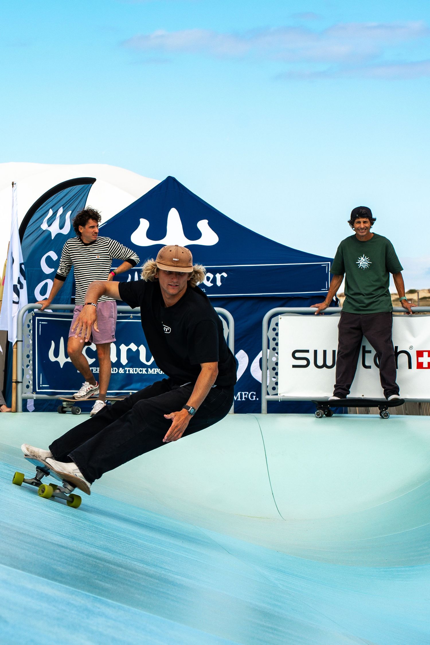 Skateboard competition on the beach, athletes performing tricks with ocean in the background, dynamic movement and vibrant summer atmosphere