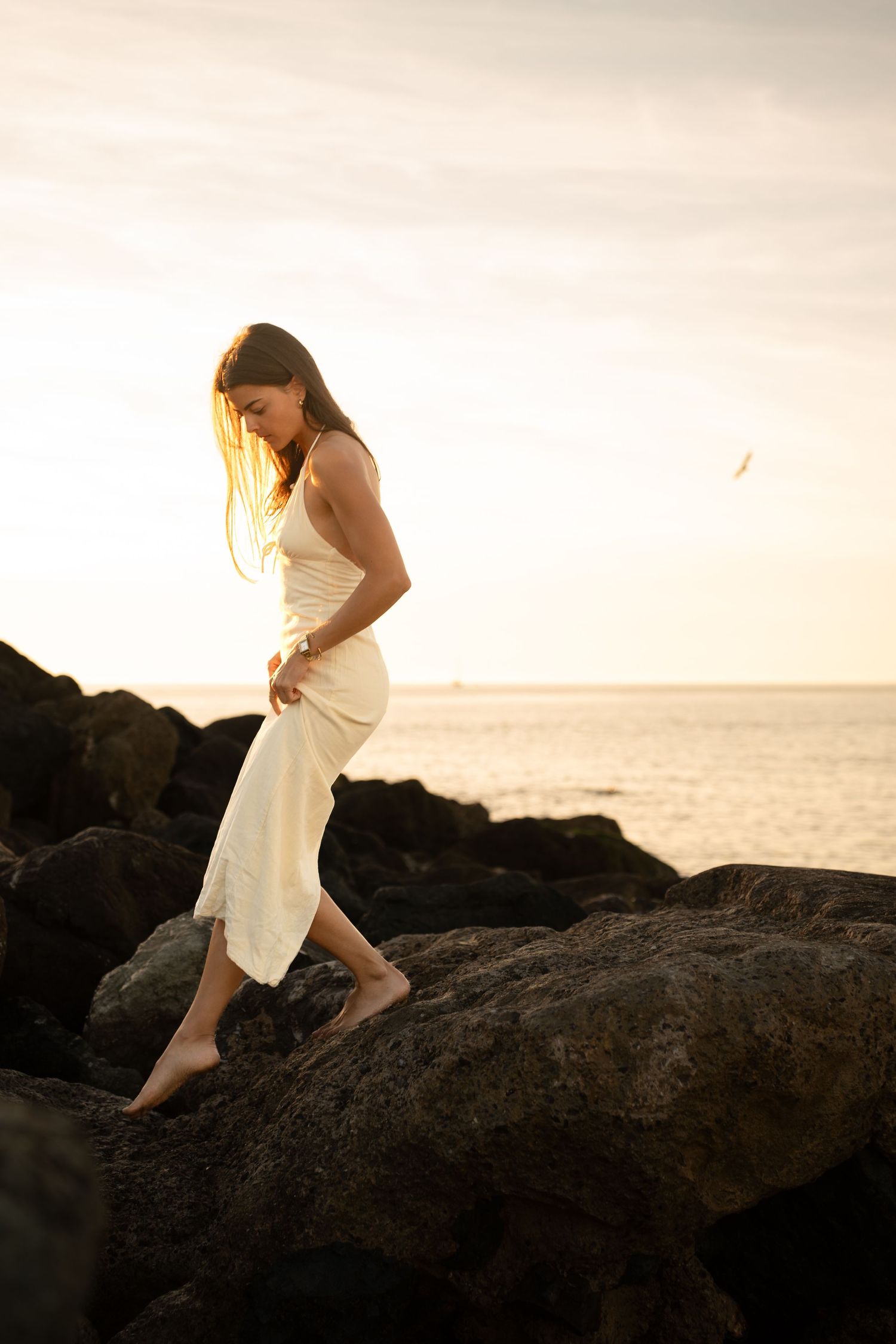 Portrait of a woman on the beach in warm natural light, with ocean and soft tones creating a cinematic mood.