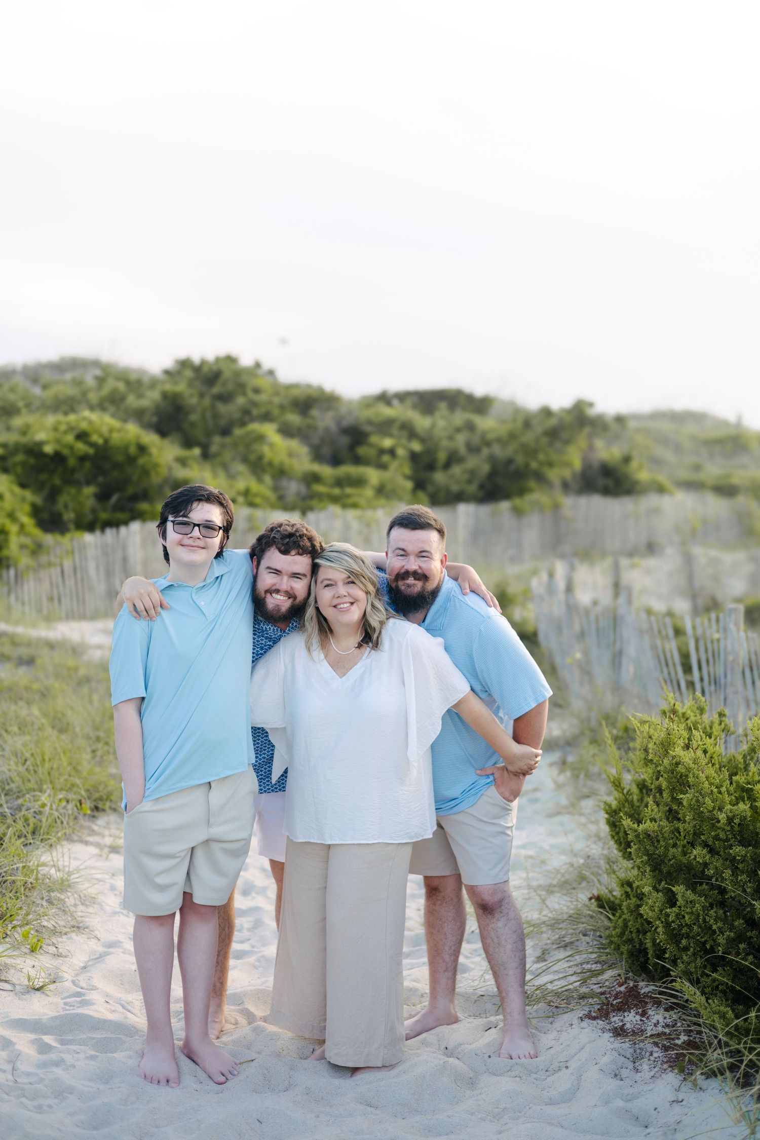 Group photo on beach with people wearing coordinated blue and white outfits.