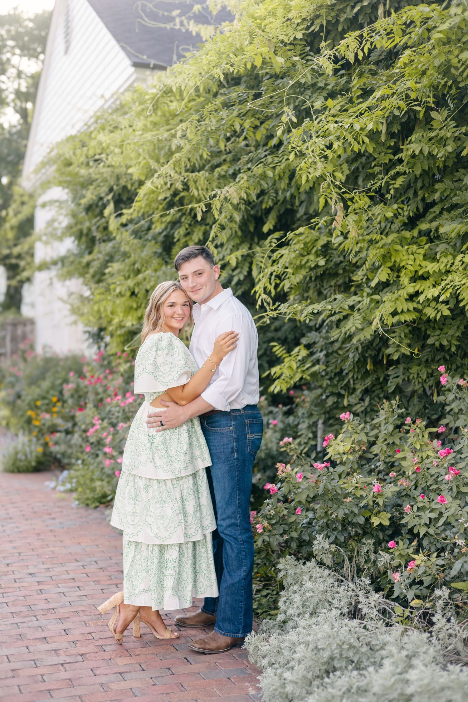Romantic garden portraits by flowering bushes and brick walkway.