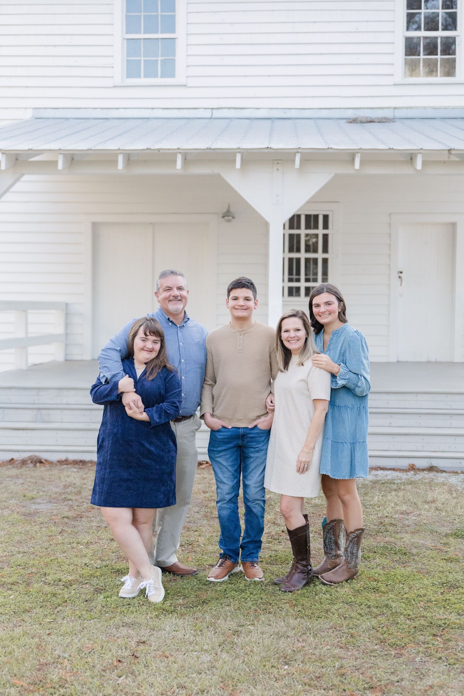 A group poses playfully together in front of a white colonial style building.