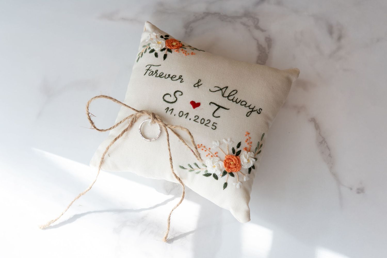 A wedding invitation suite with delicate orange floral details and string accents displayed on a marble surface.