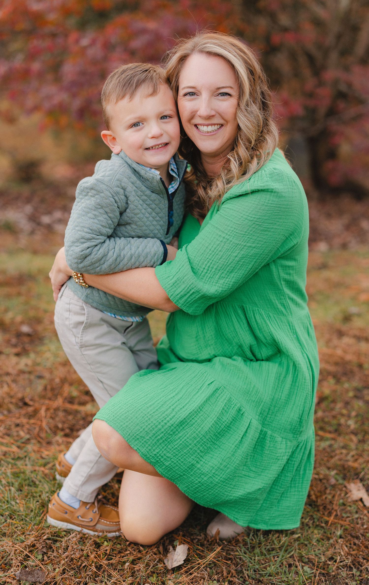 Sweet autumn portrait series showing tender moments between parent and child in a green dress against fall foliage.