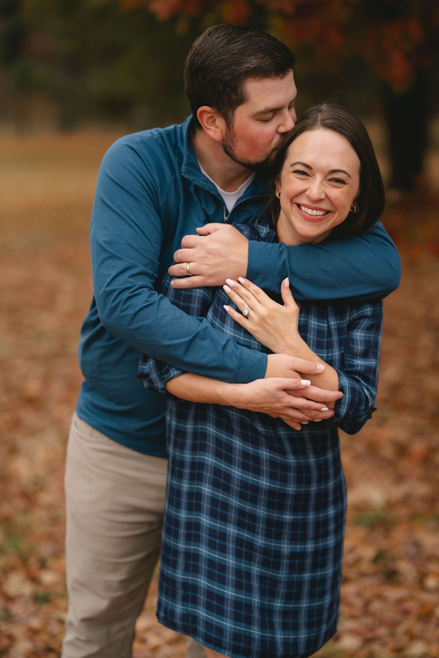 A playful engagement photo sequence showing a couple embracing in autumn leaves wearing blue and plaid.