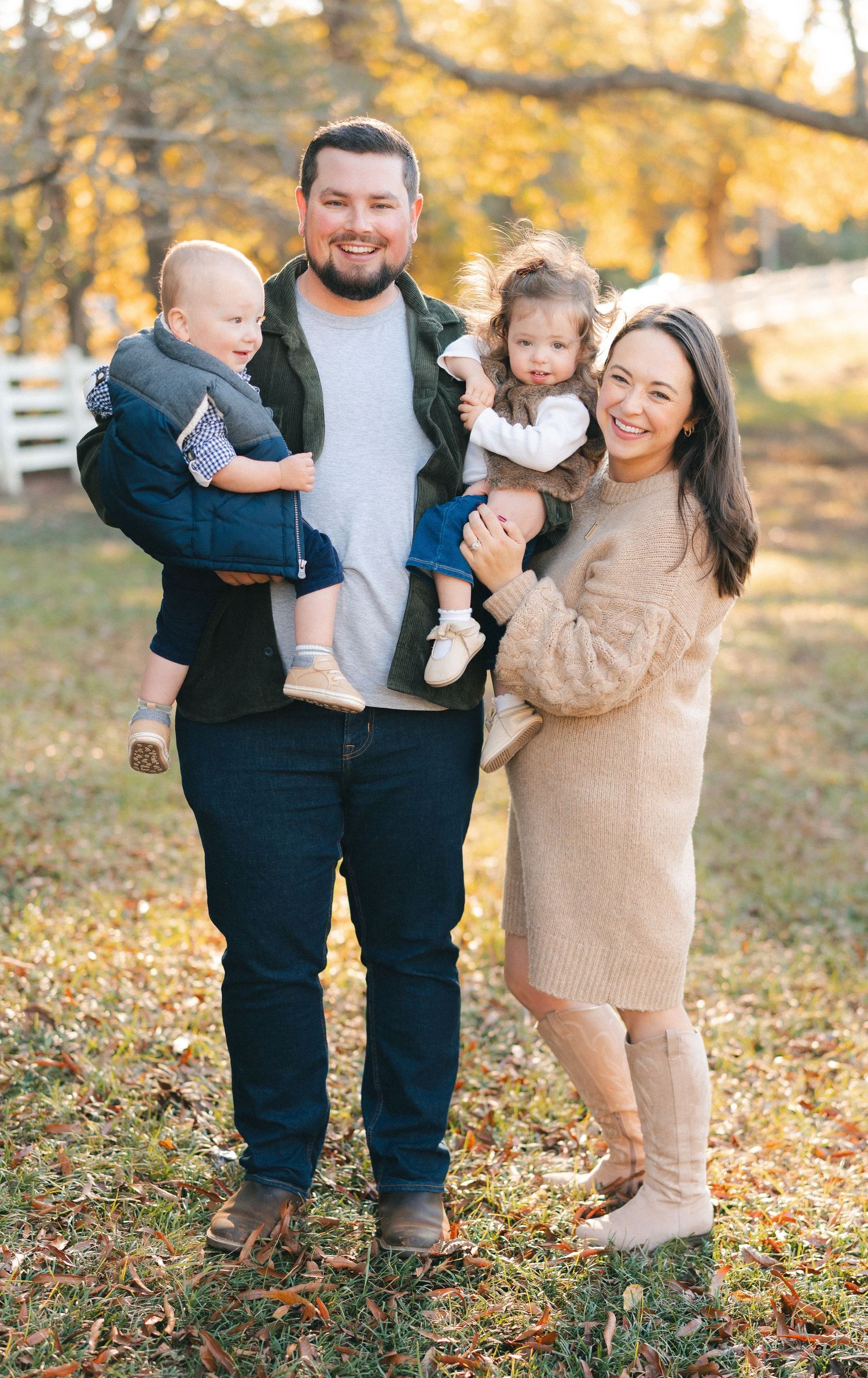 Happy family poses together on an autumn day with golden leaves in the background.