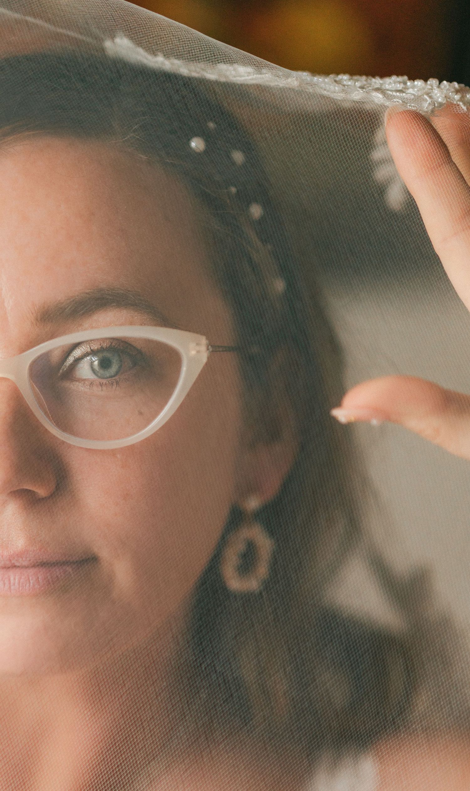 Close-up shots of someone adjusting delicate white eye makeup through a sheer veil.