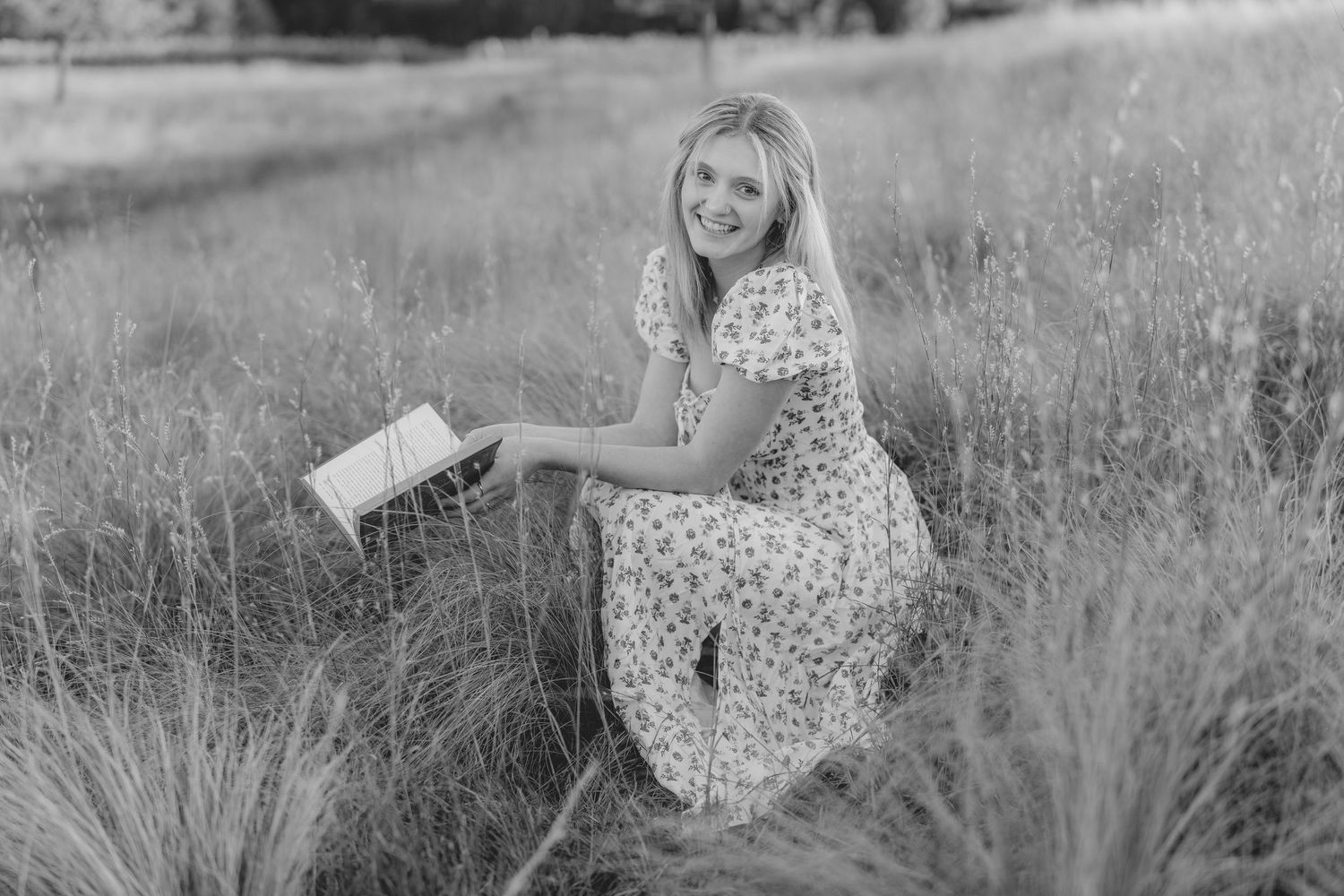 Black and white portrait series of someone in a polka dot dress posing in a grassy field.