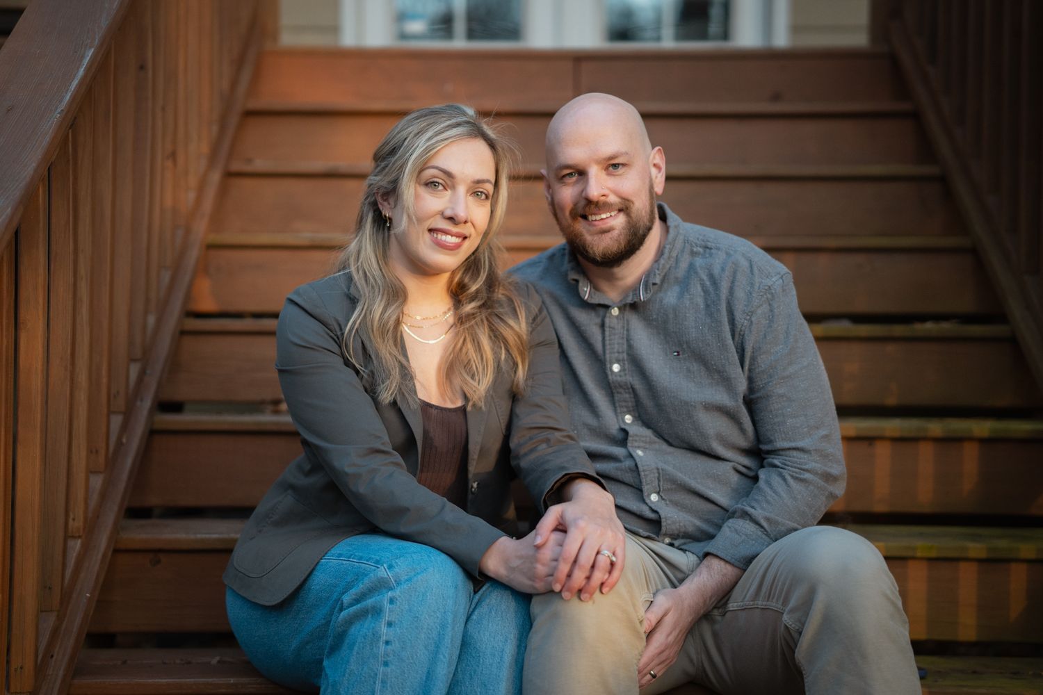 A couple sits together on wooden steps during a cozy outdoor photoshoot.