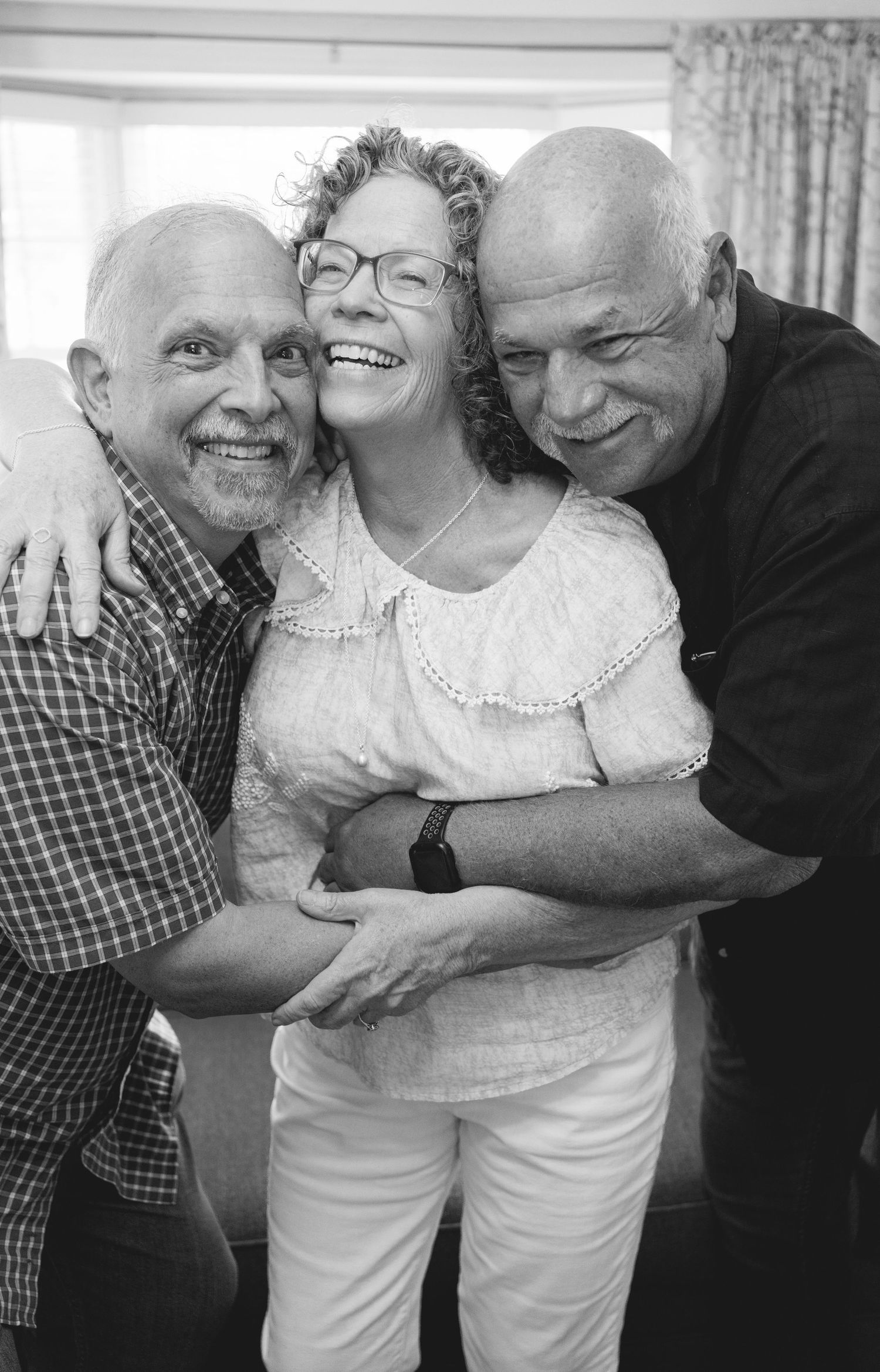 Black and white photo series showing three people embracing and laughing together.