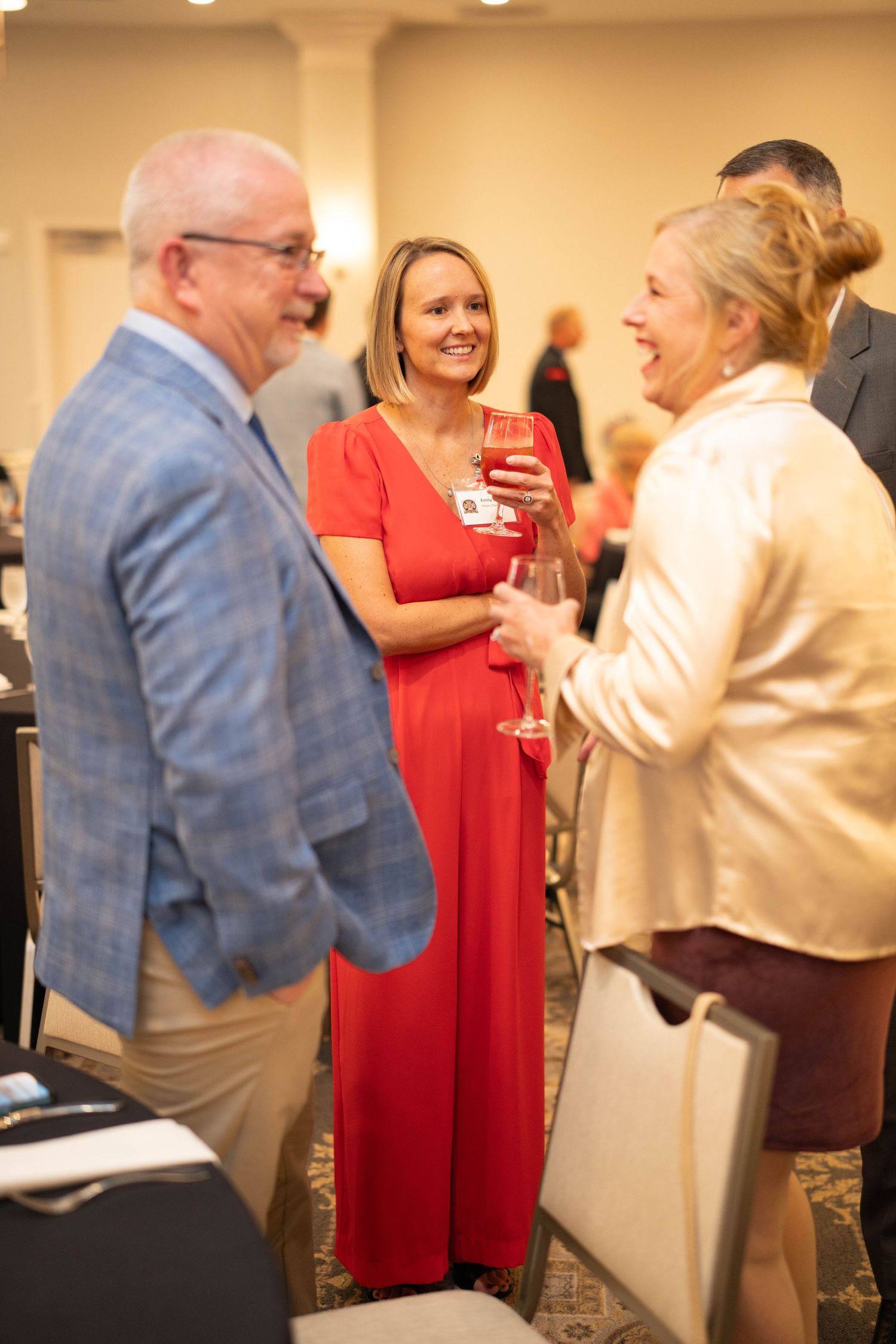 Social gathering with people mingling in formal attire at indoor event.