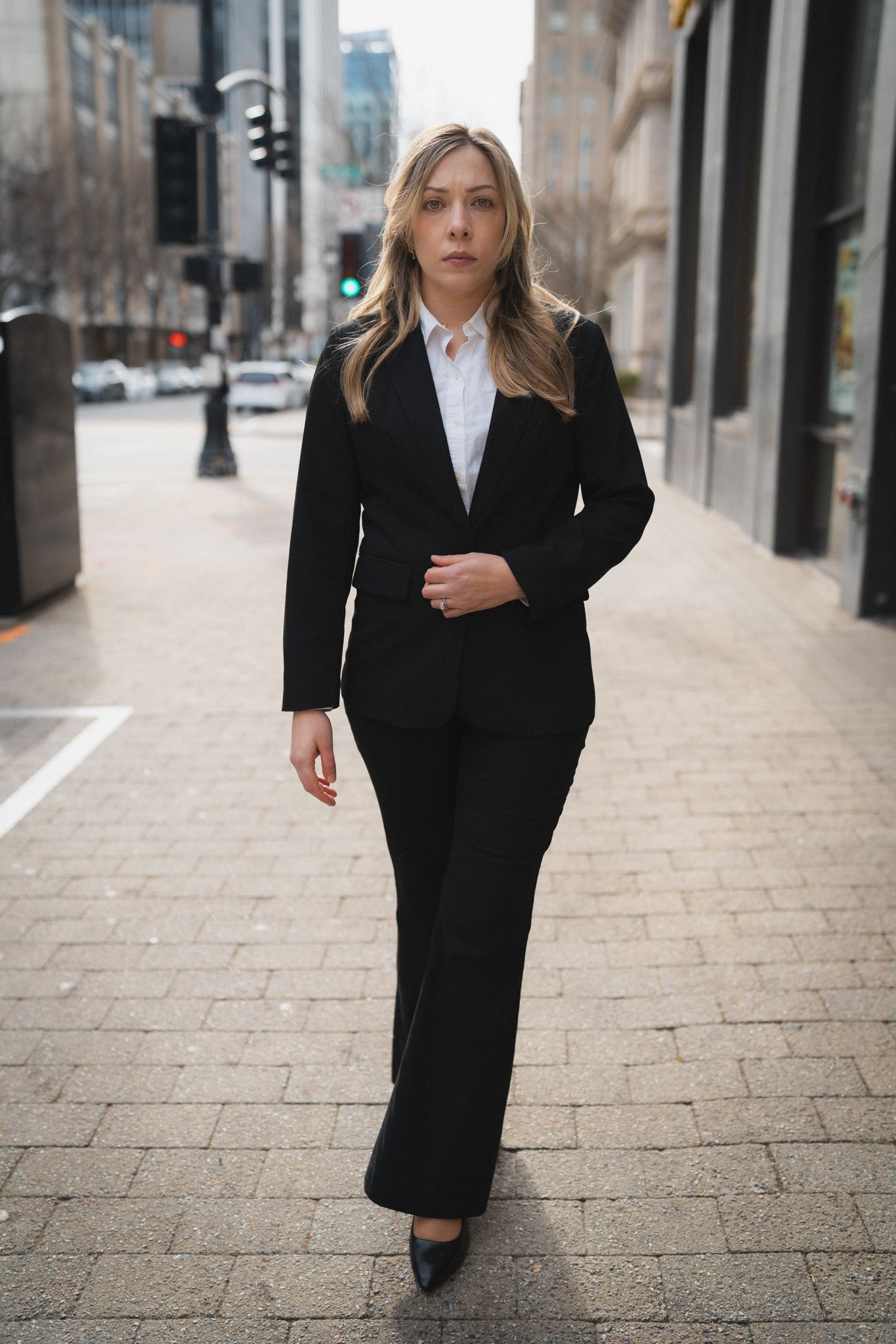 A series of photos showing someone in a black business suit walking on a stone paved street in an urban setting.