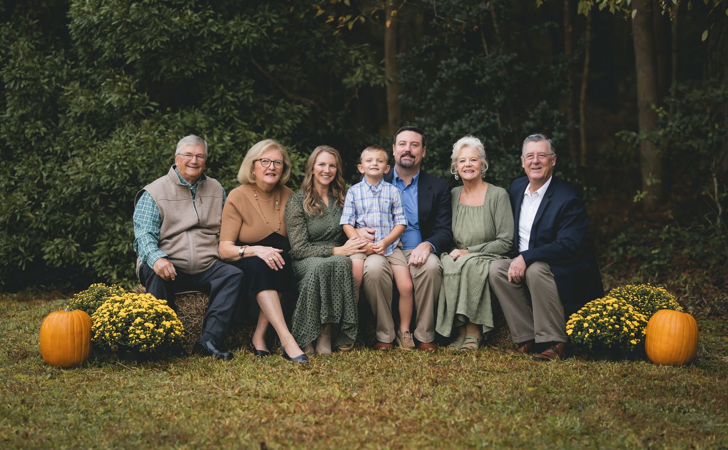 Extended family poses for an autumn portrait with pumpkins and fall foliage.