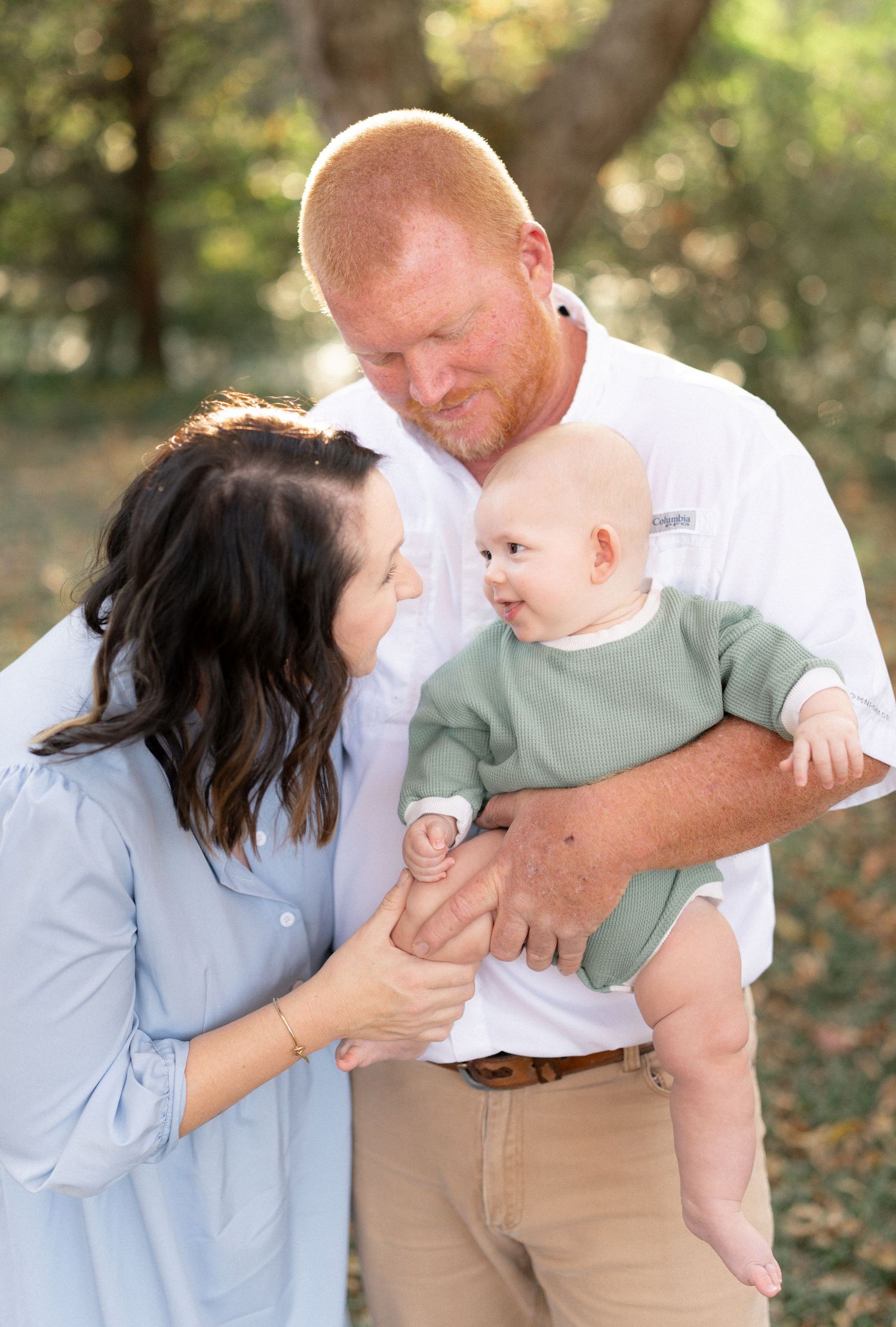 Intimate outdoor family portrait with baby in soft natural lighting.