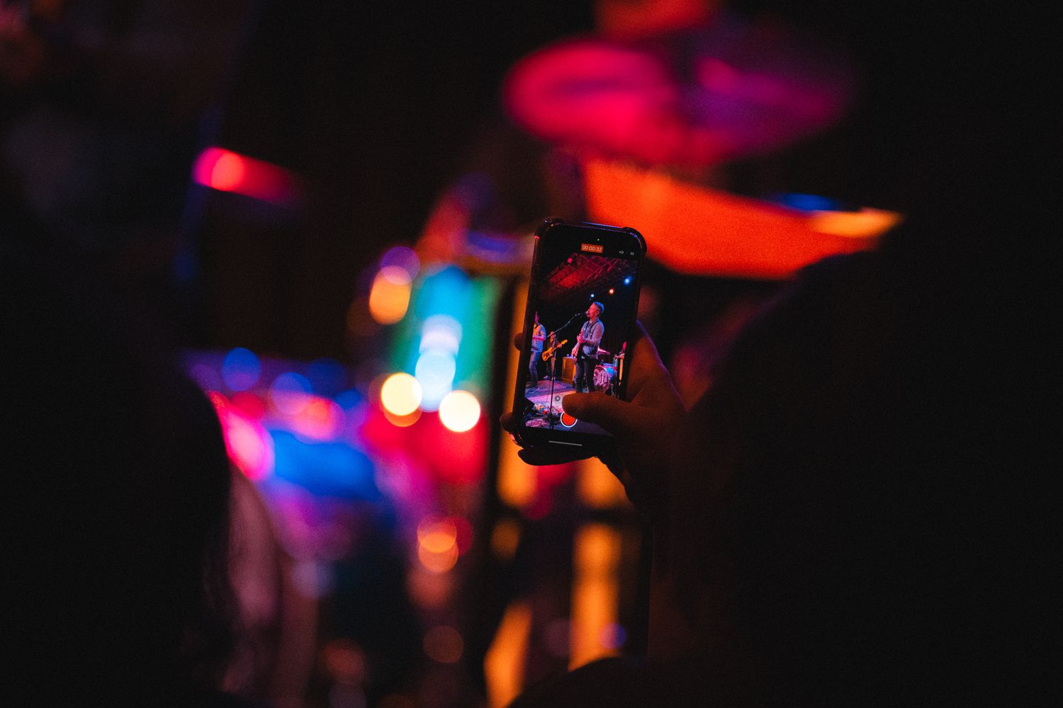 Concert stage lights create colorful bokeh effect in dark performance space.