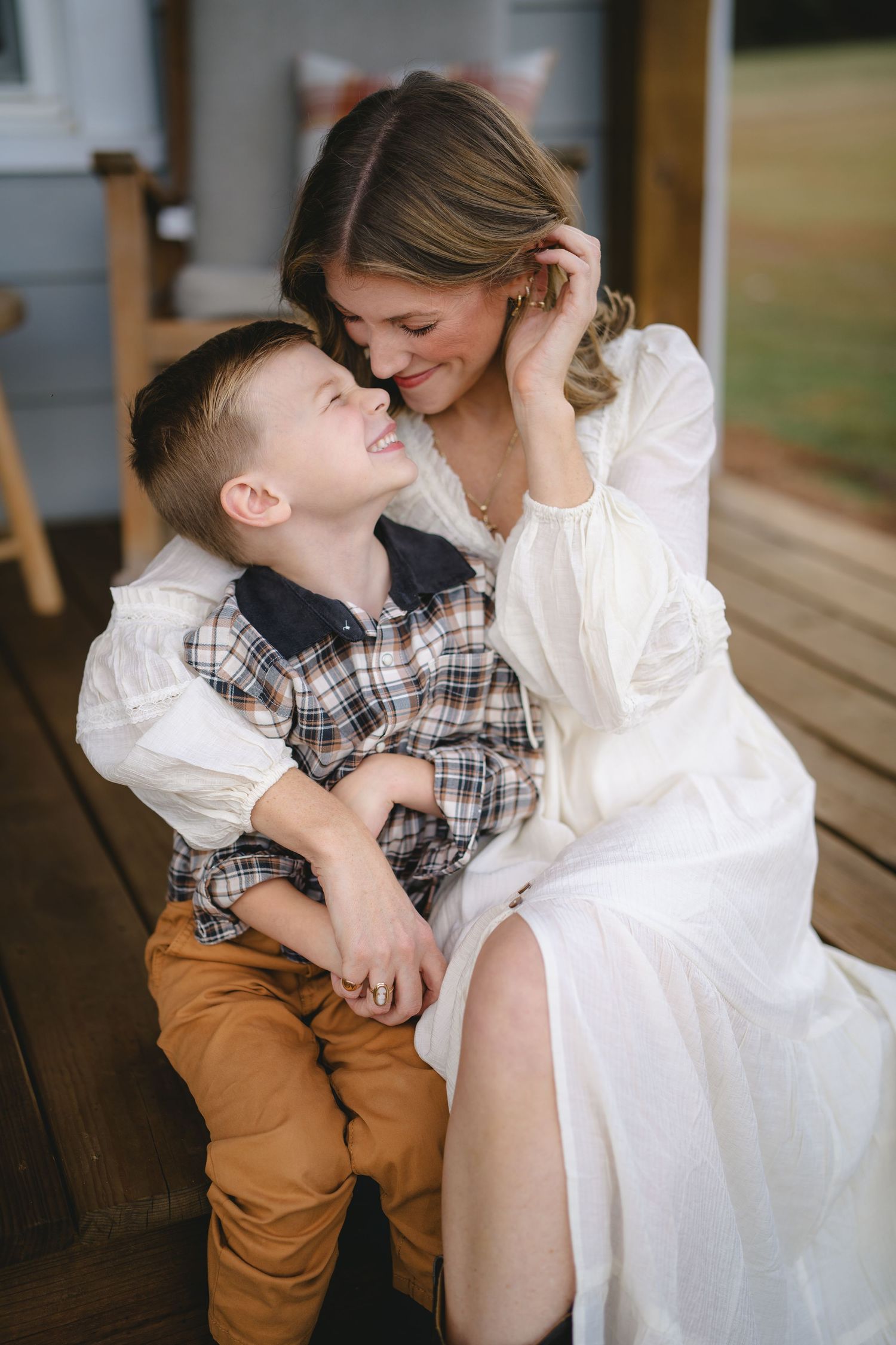 A tender moment captured between a child in plaid and someone in white sitting together on wooden steps.