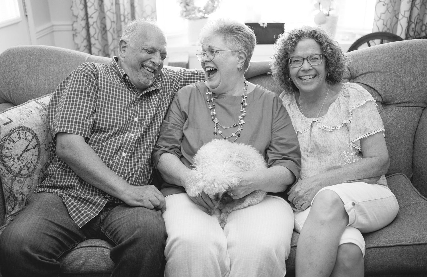 Multi-generational family relaxing together on a cozy gray couch during casual gathering.