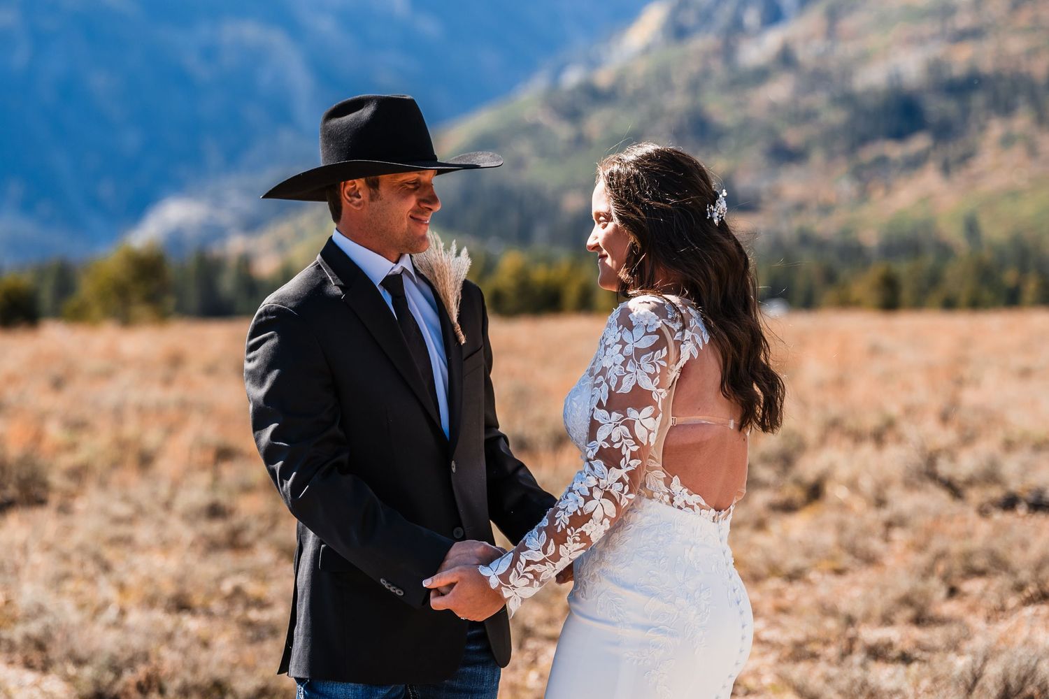 A couple shares a romantic moment during their wedding ceremony in front of scenic mountain views.