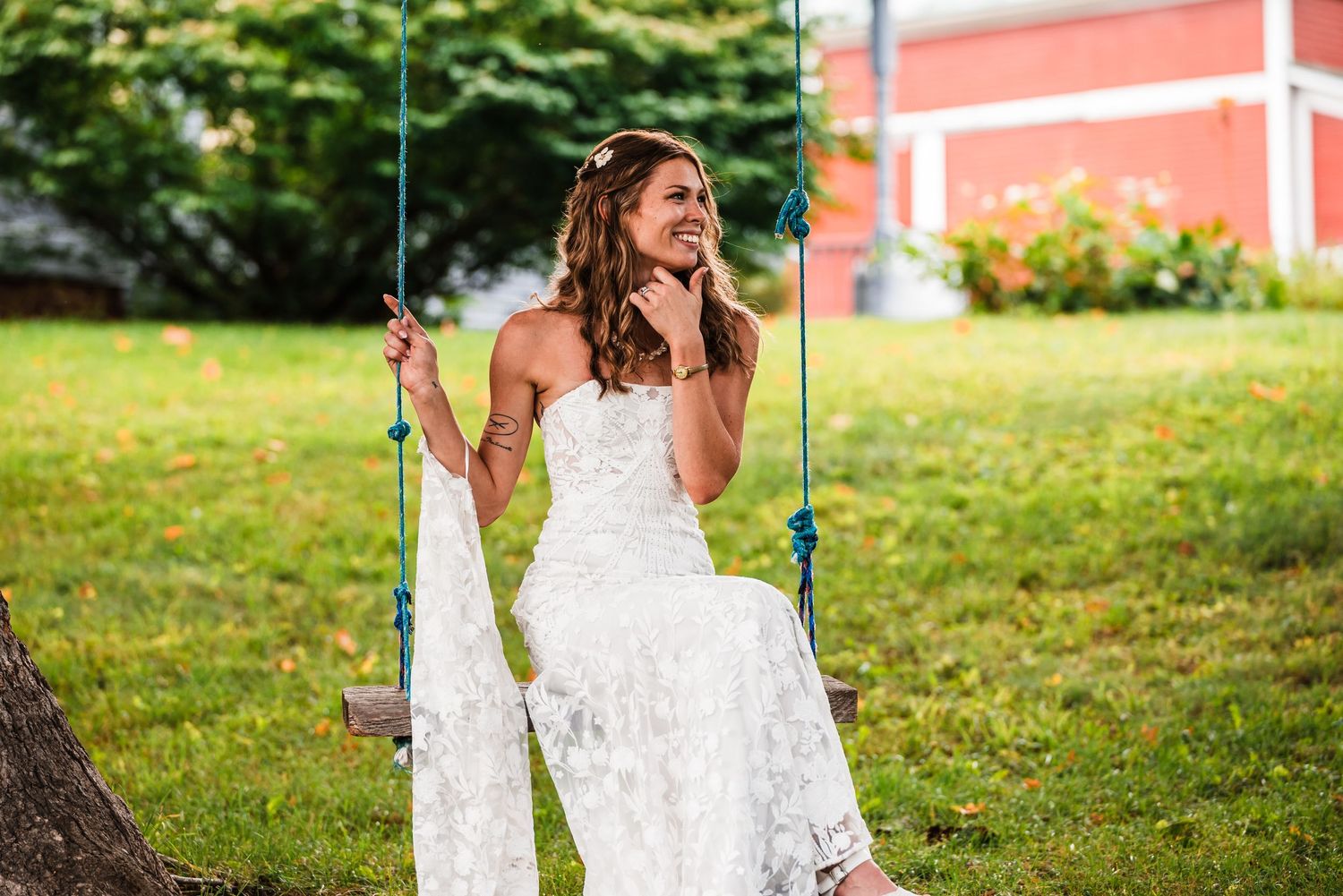 A white lace wedding dress photographed on a tree swing in a garden setting.
