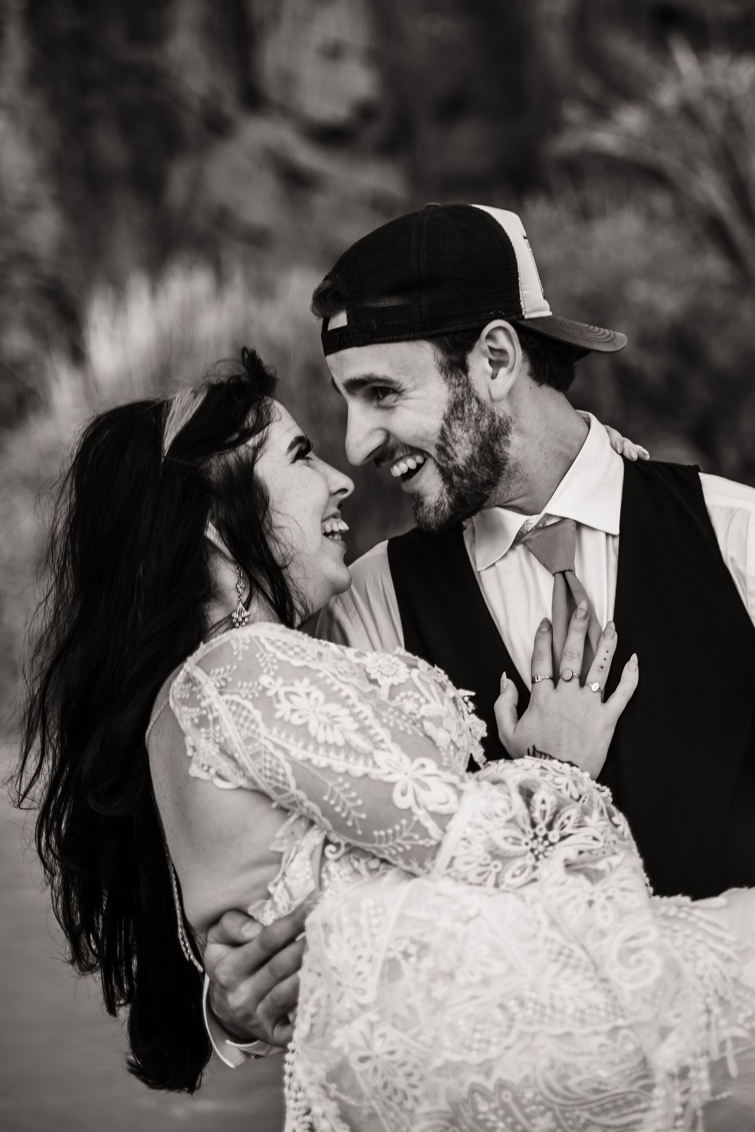 Black and white portrait of a joyful couple sharing an intimate moment in wedding attire.