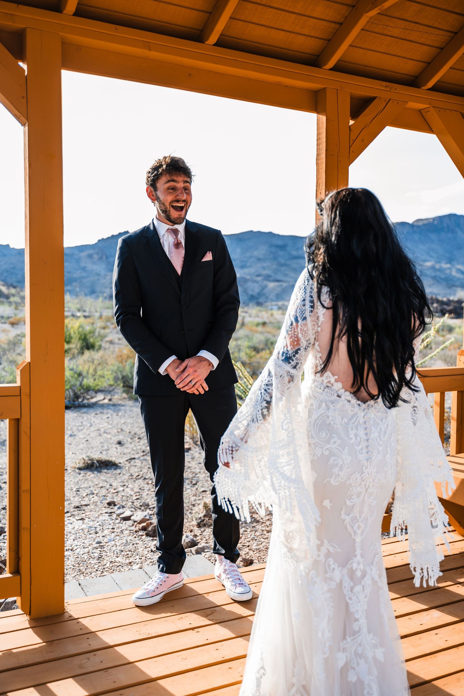 Wedding ceremony moment on rustic wooden deck with desert mountains in background.