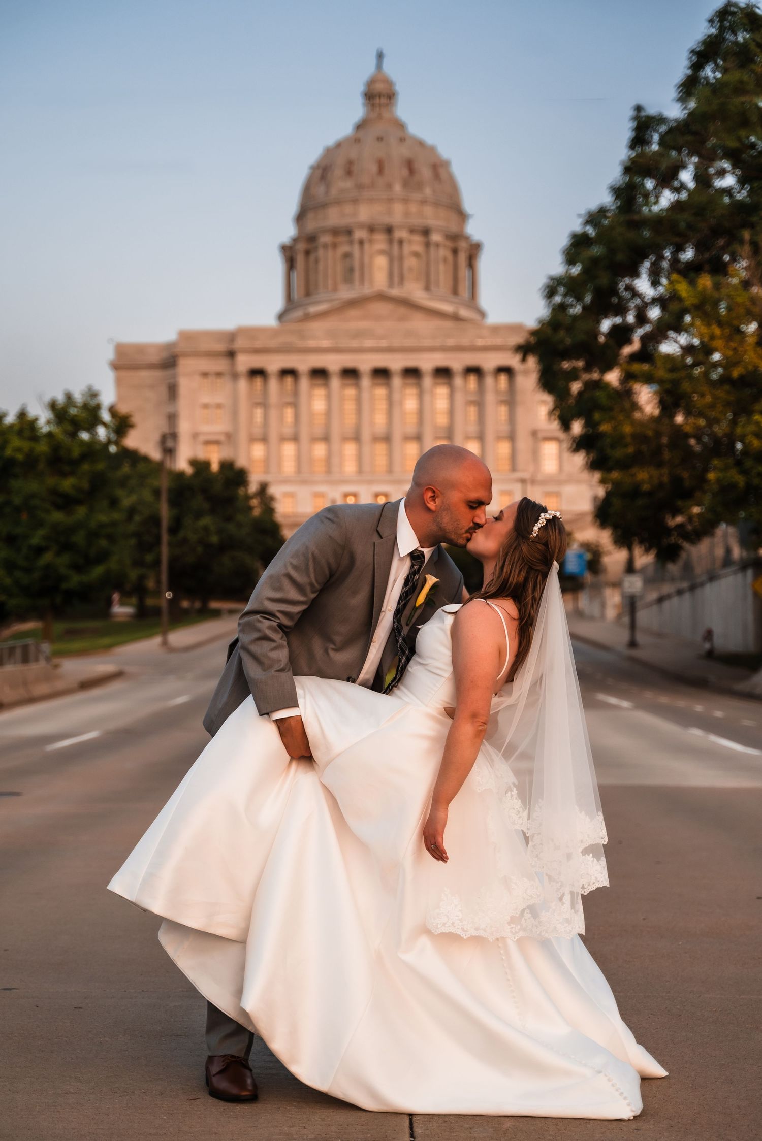 A romantic wedding portrait taken at sunset in front of a grand domed government building.