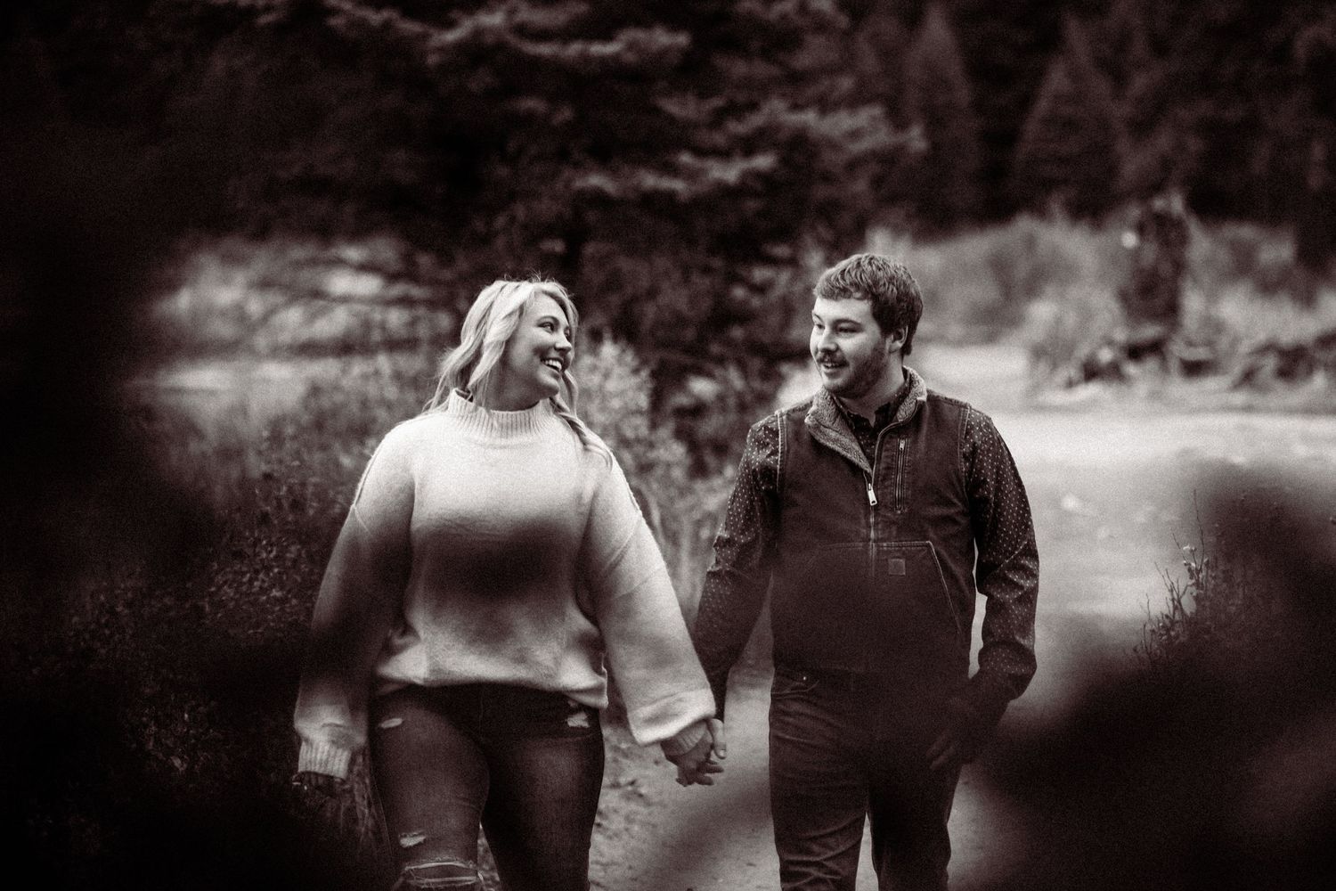 A couple walking together in a natural outdoor setting captured in black and white.