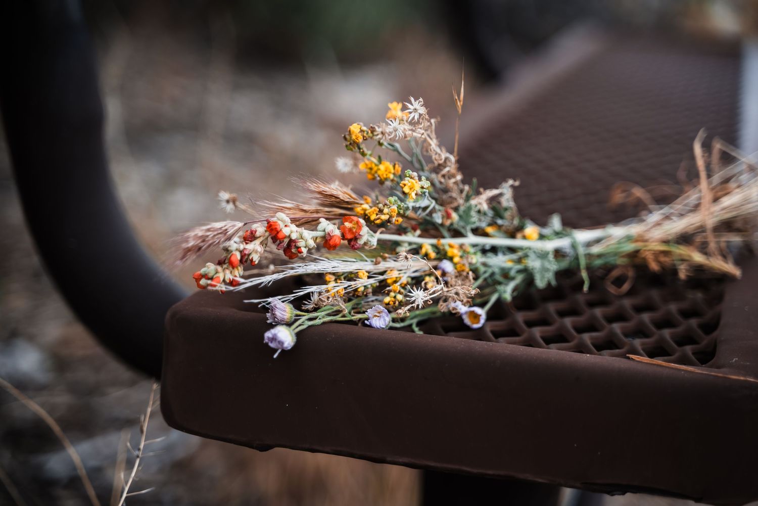 A bouquet of dried yellow wildflowers and white baby's breath lying on a brown wooden surface.