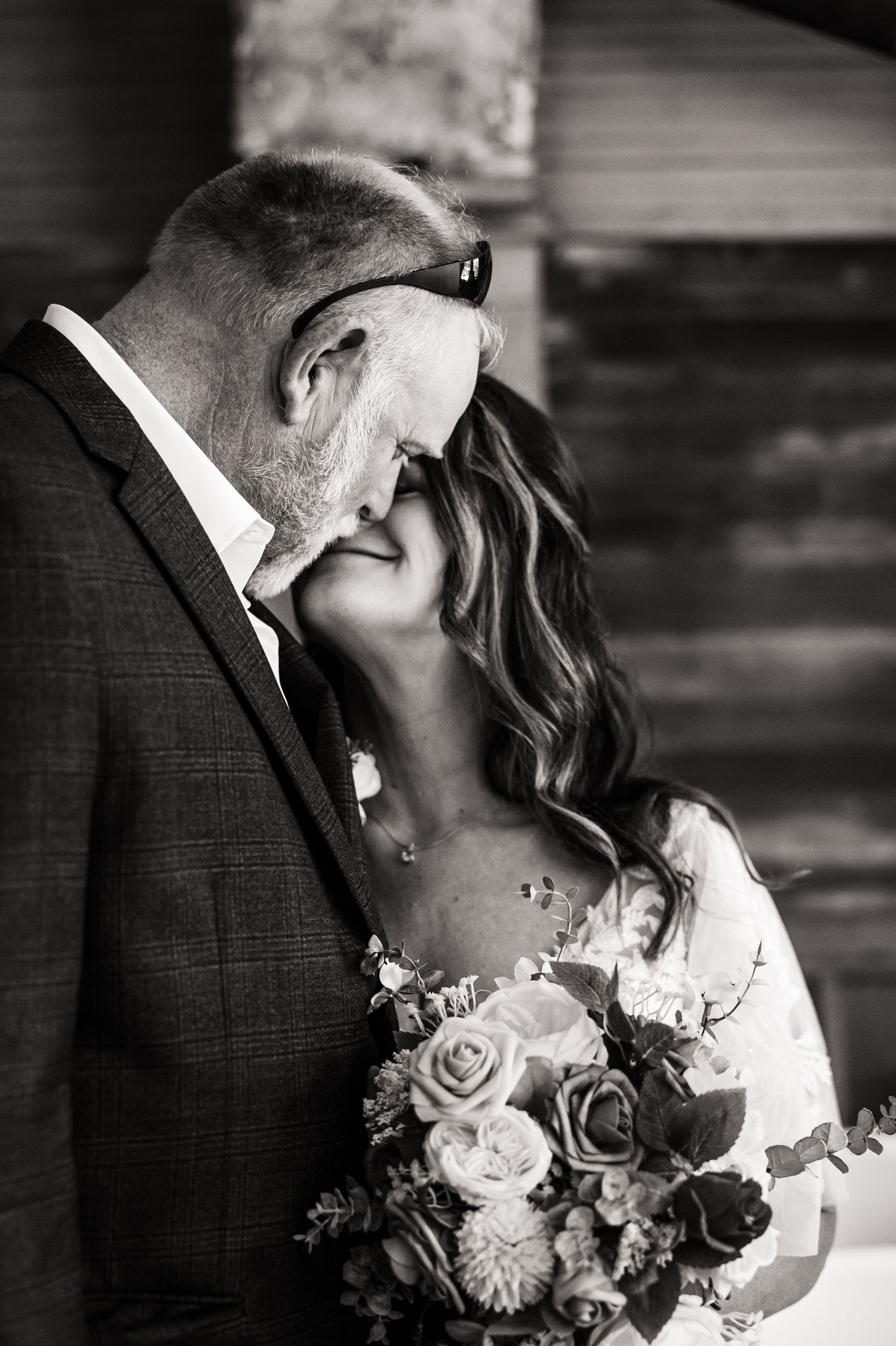 Intimate black and white wedding portrait with couple holding a bouquet of roses.