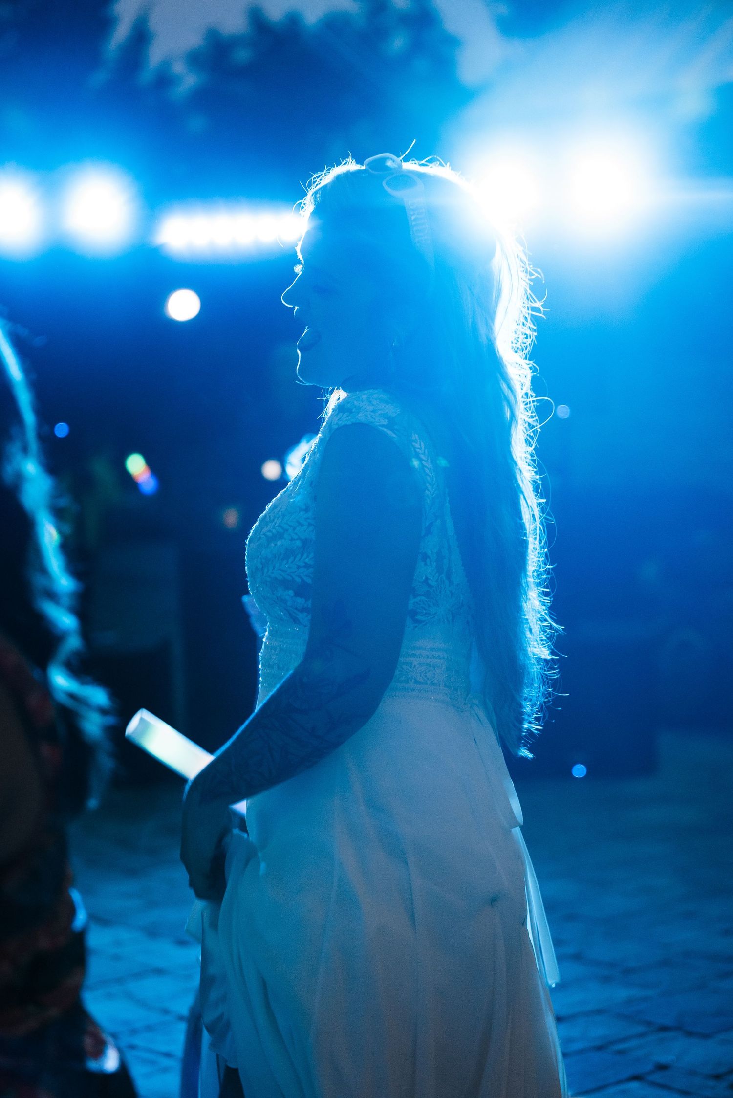 A backlit silhouette of a bride in a white dress against blue stage lighting.