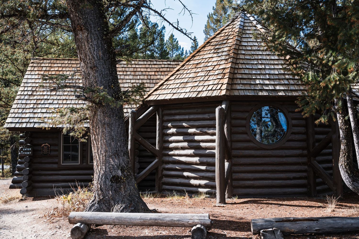 Row of rustic log cabins nestled among pine trees at a mountain lodge retreat.