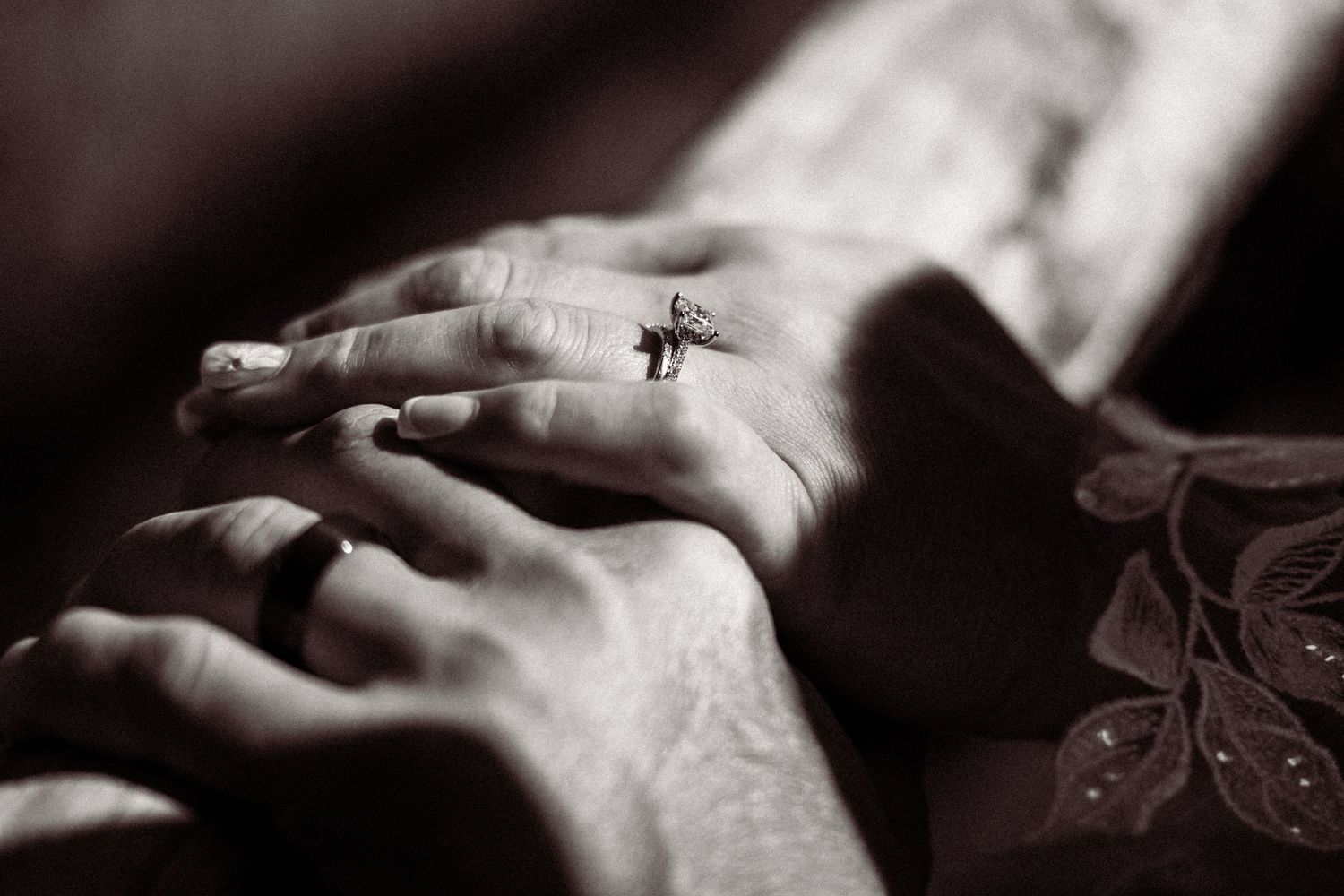 Close-up of hands with a small cross tattoo in black and white photography.