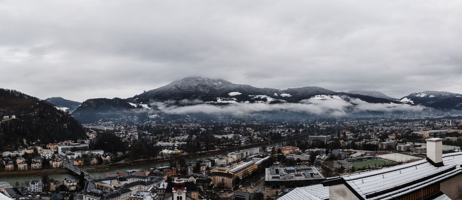 Panoramic winter mountain landscape with snow-covered peaks and cloudy skies.