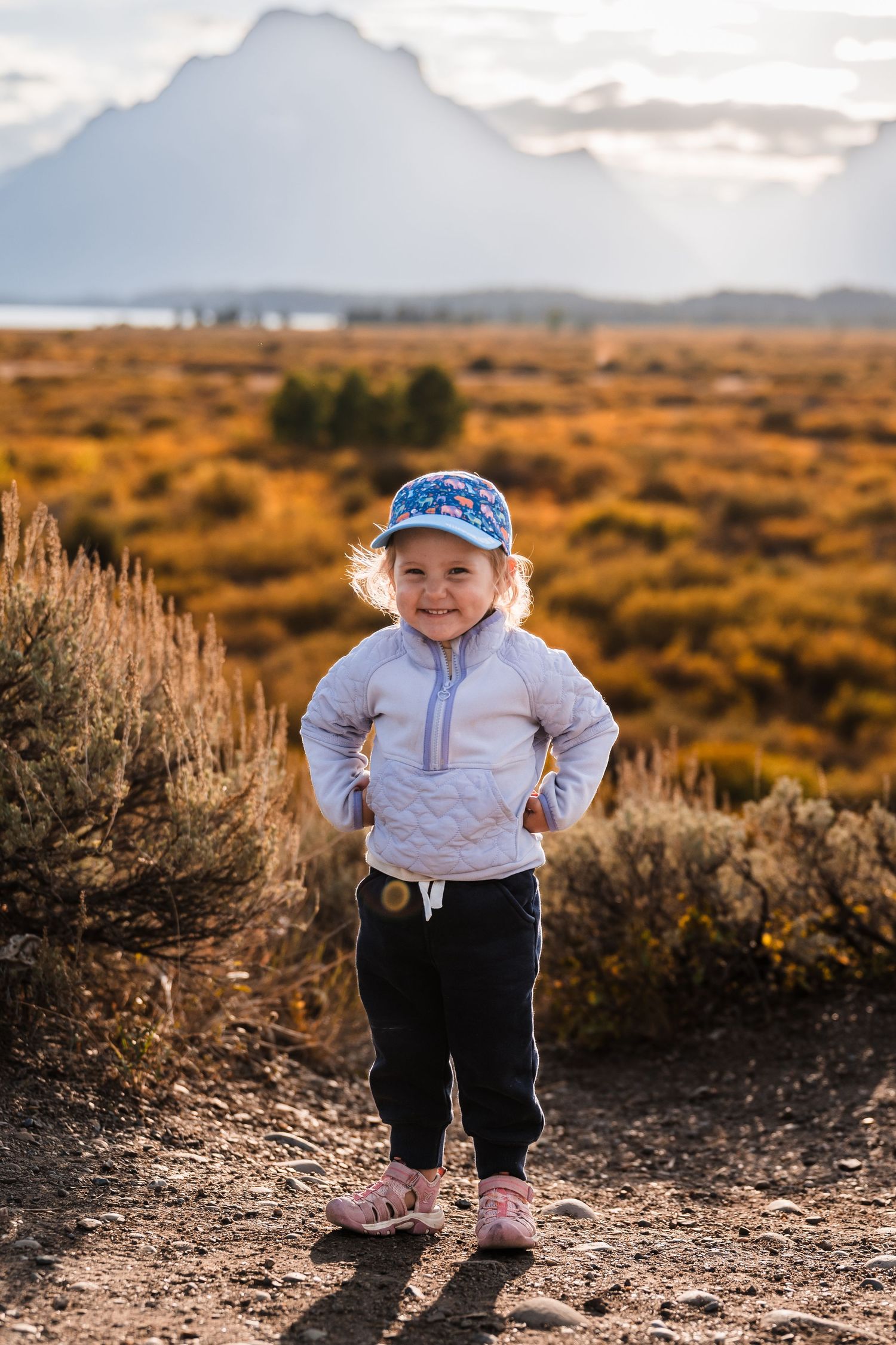 Small figure explores sagebrush-covered terrain with mountain backdrop.