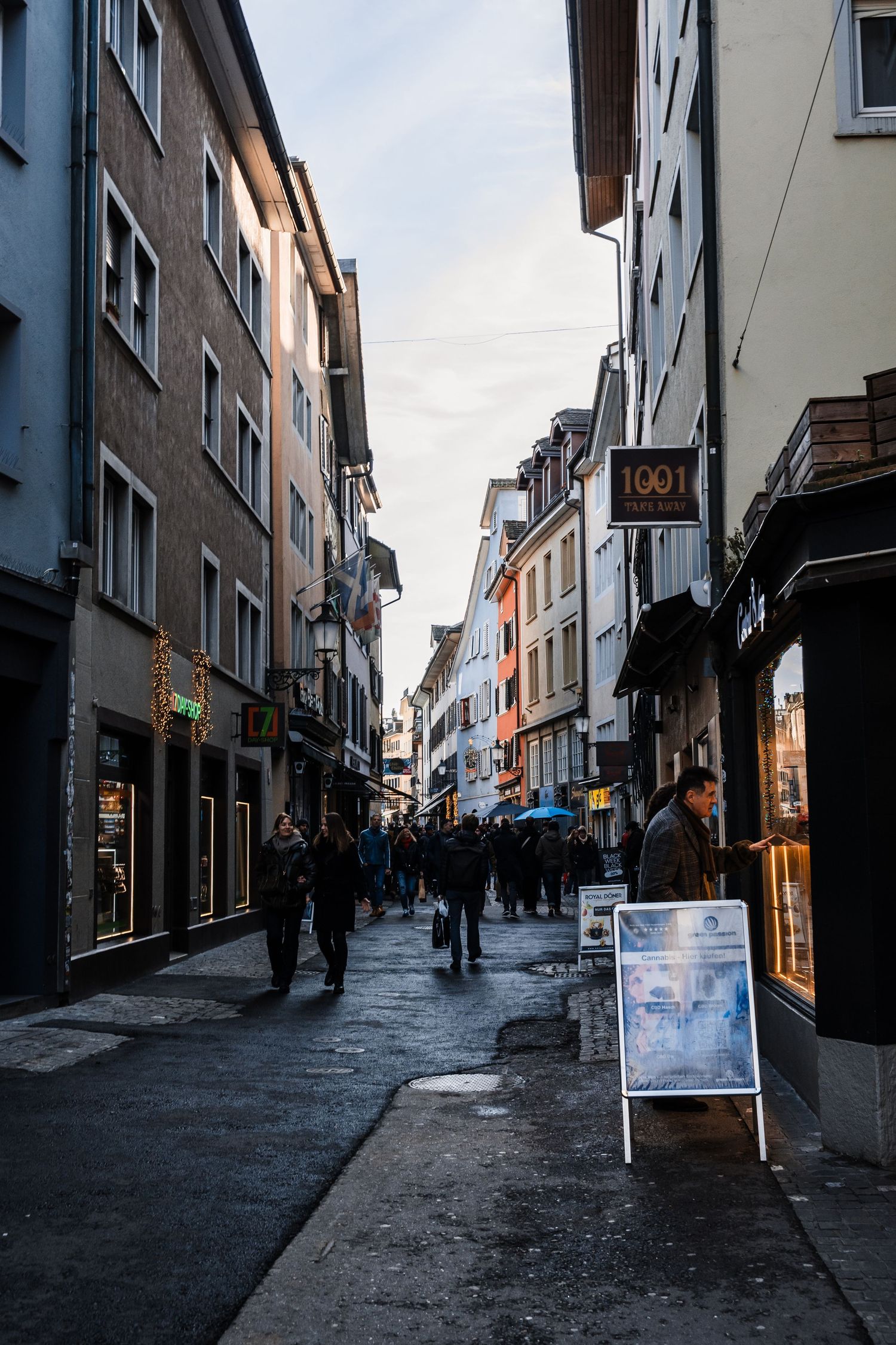 A series of four photos showing a narrow European street with shops and buildings in diminishing light.