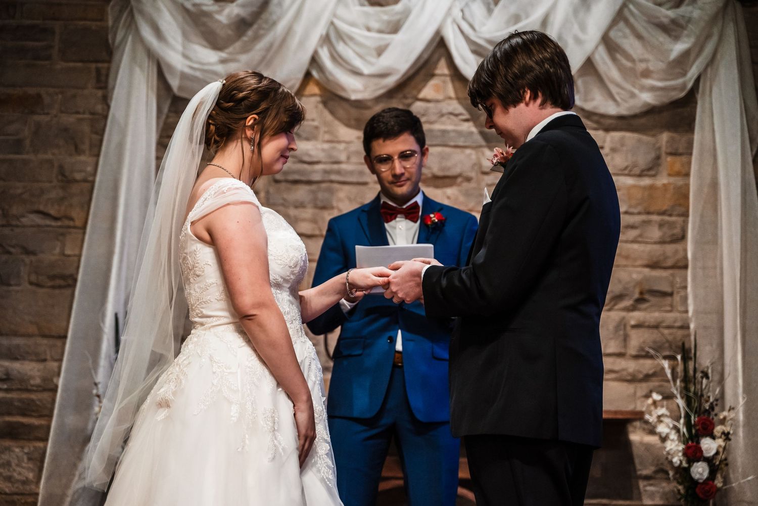 Wedding ceremony in progress under white fabric draping in historic stone church.