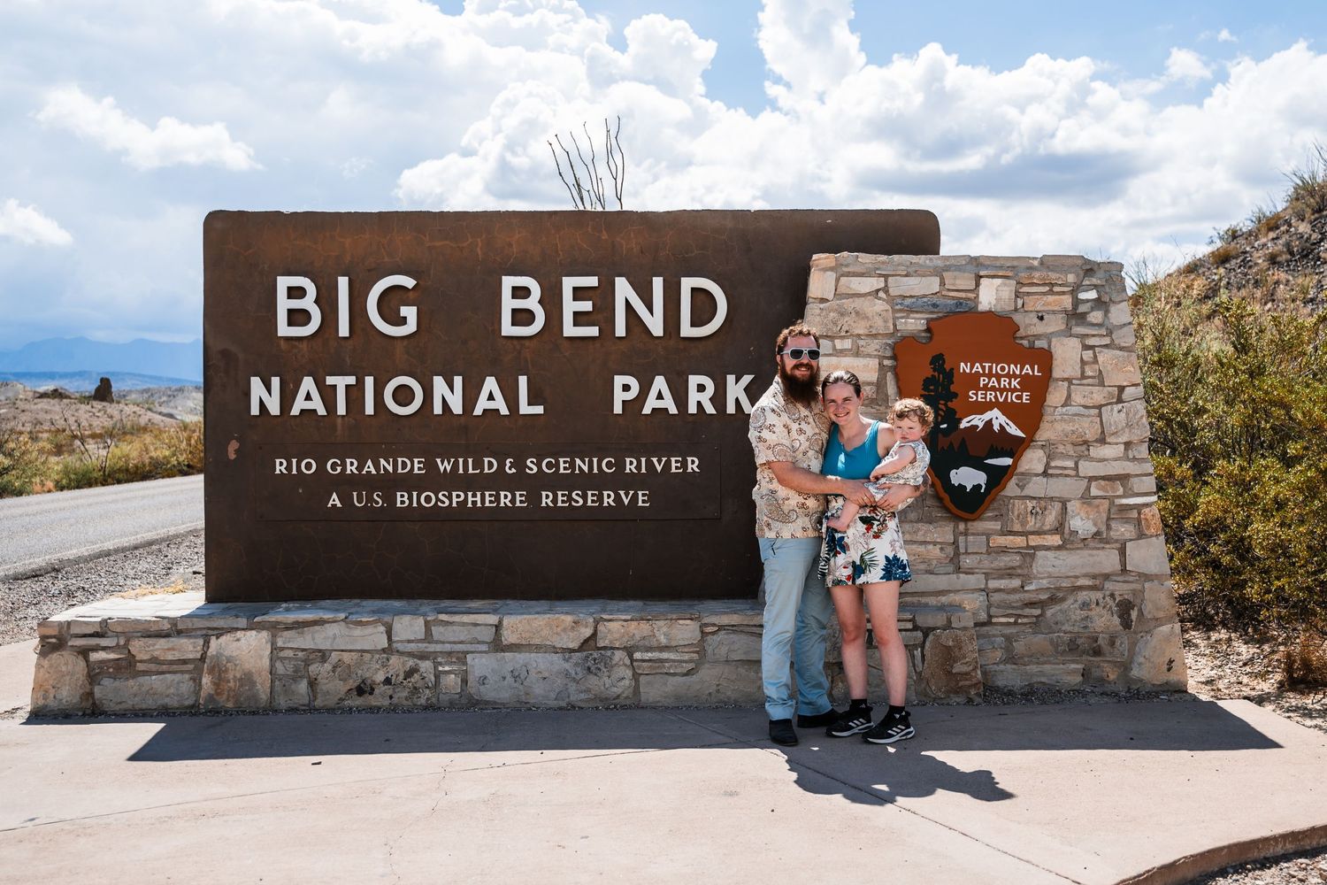 Stone entrance sign for Big Bend National Park with scenic desert mountains and blue sky in the background.