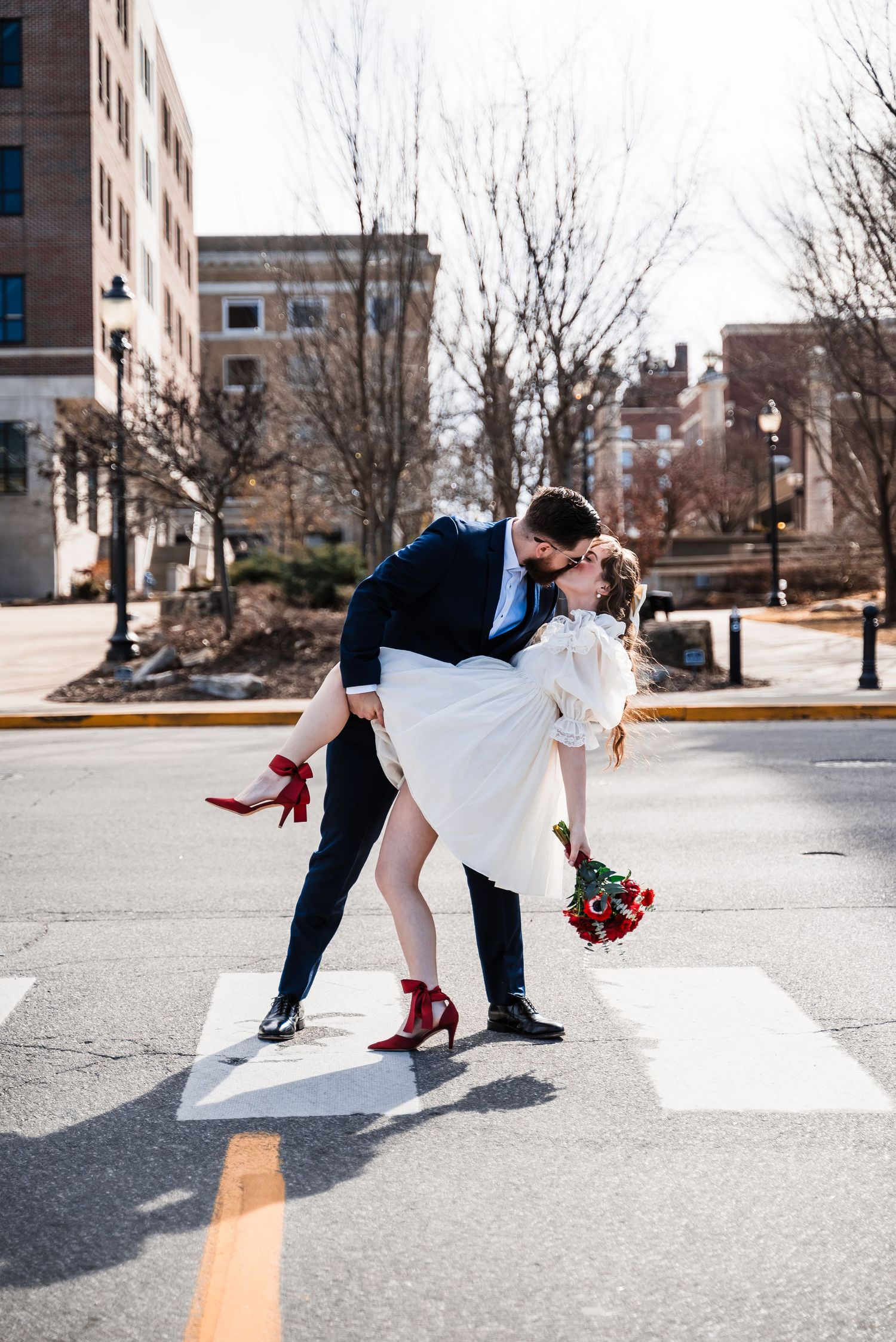 A romantic dip pose on a city street with red roses and high heels adding pops of color.