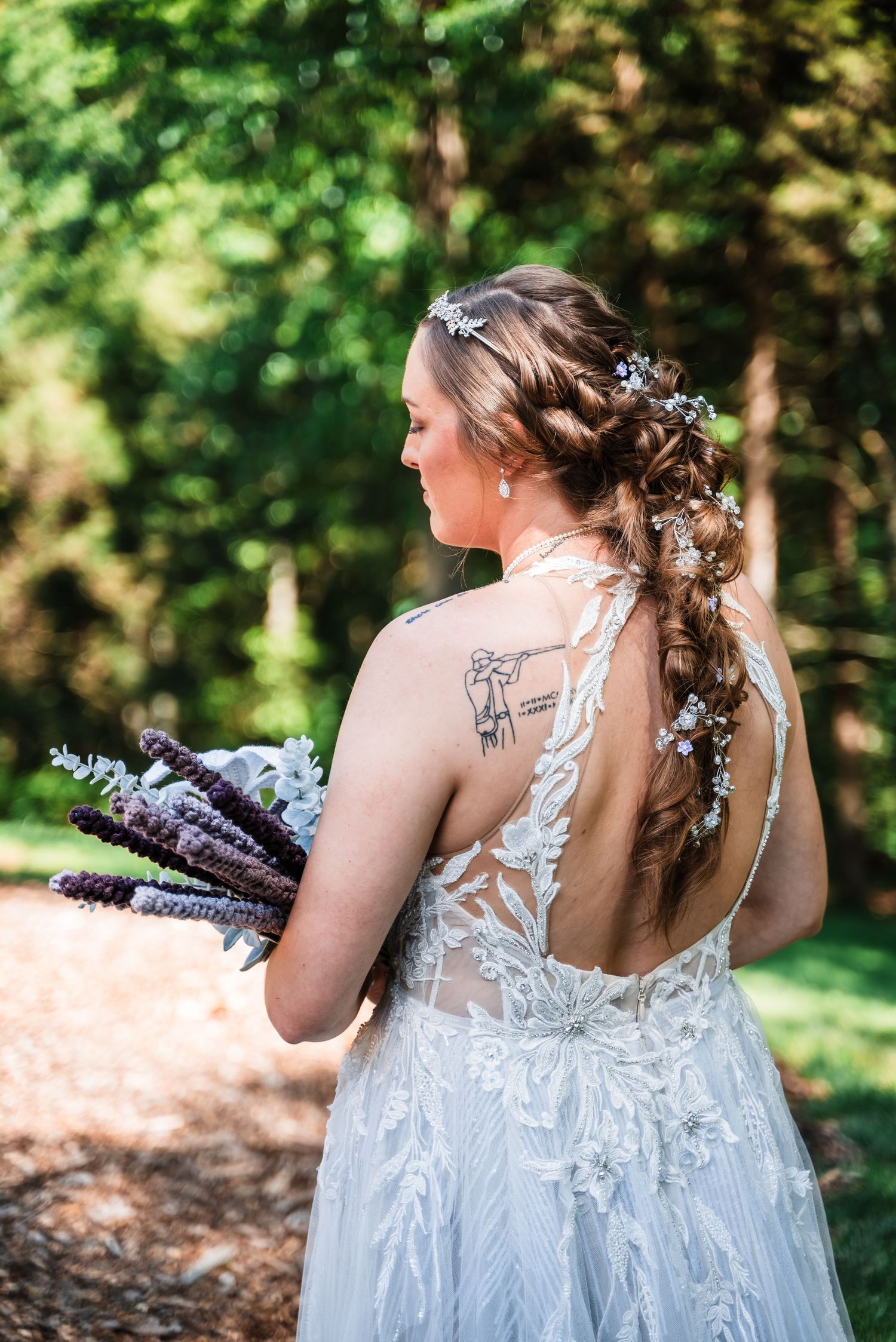 A bridal gown with delicate lace back detail and floral hair accessories, photographed in a garden setting.