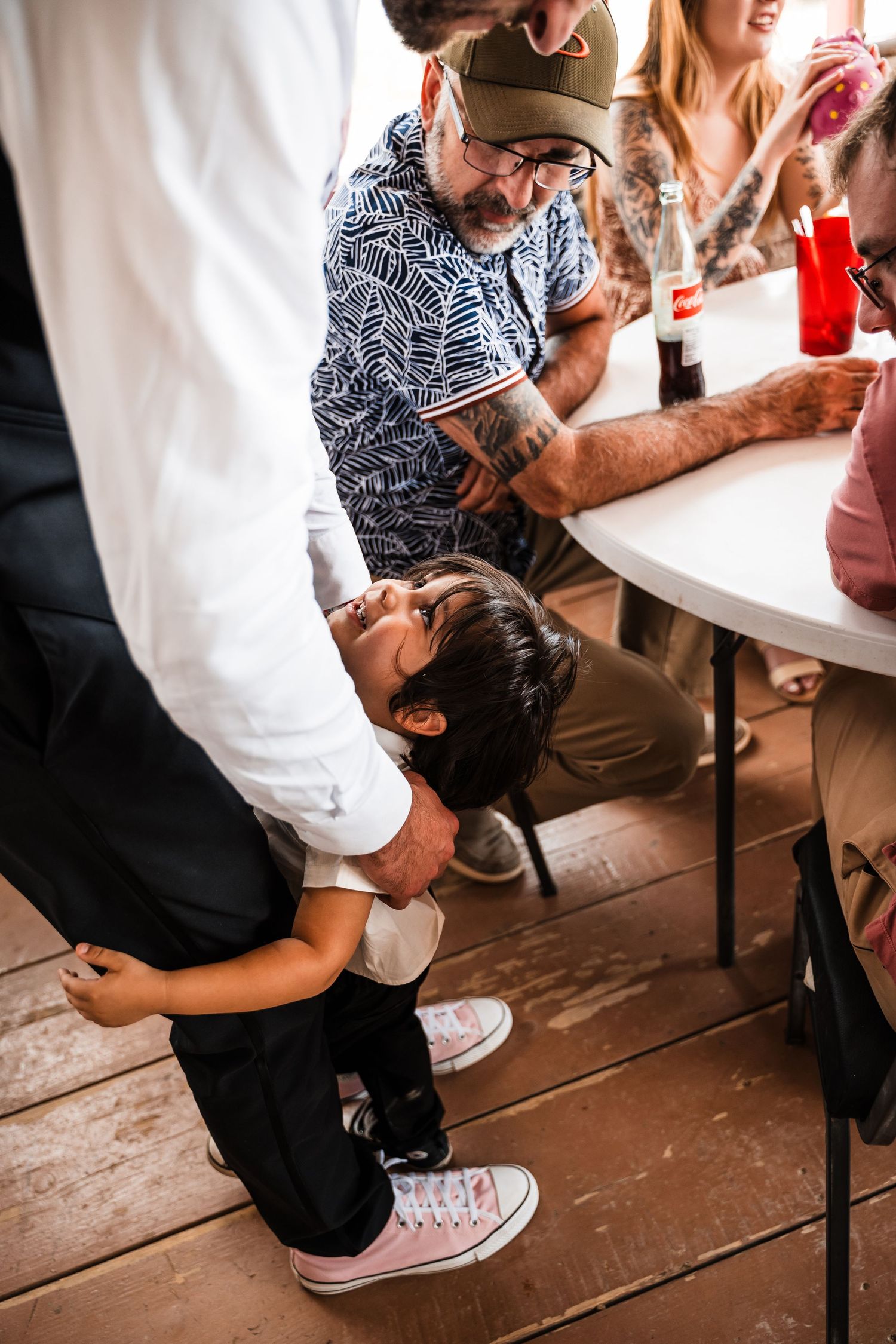 People interacting at casual restaurant with wooden floors and white tables.