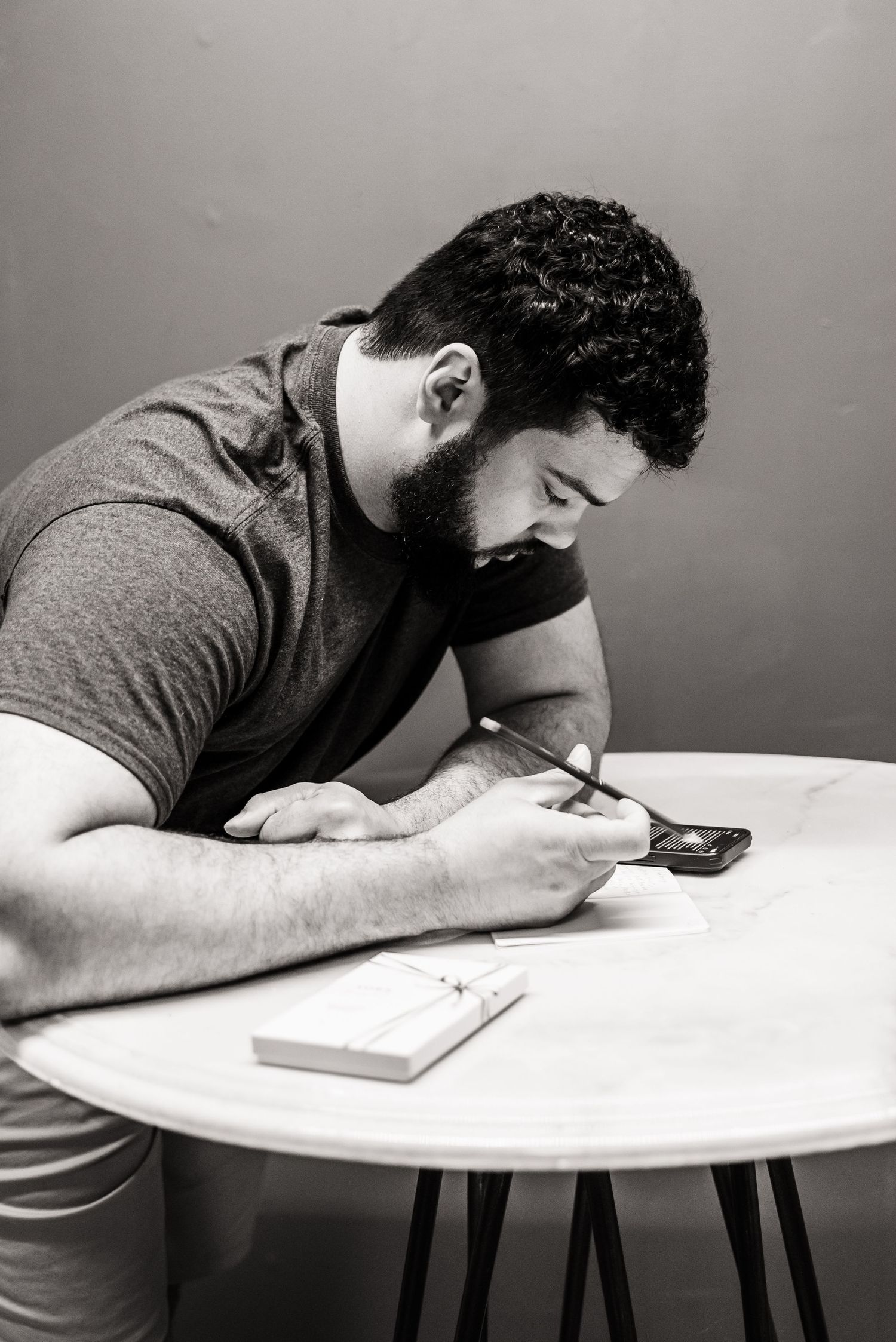 Person in casual attire focused on writing or texting at a round table.
