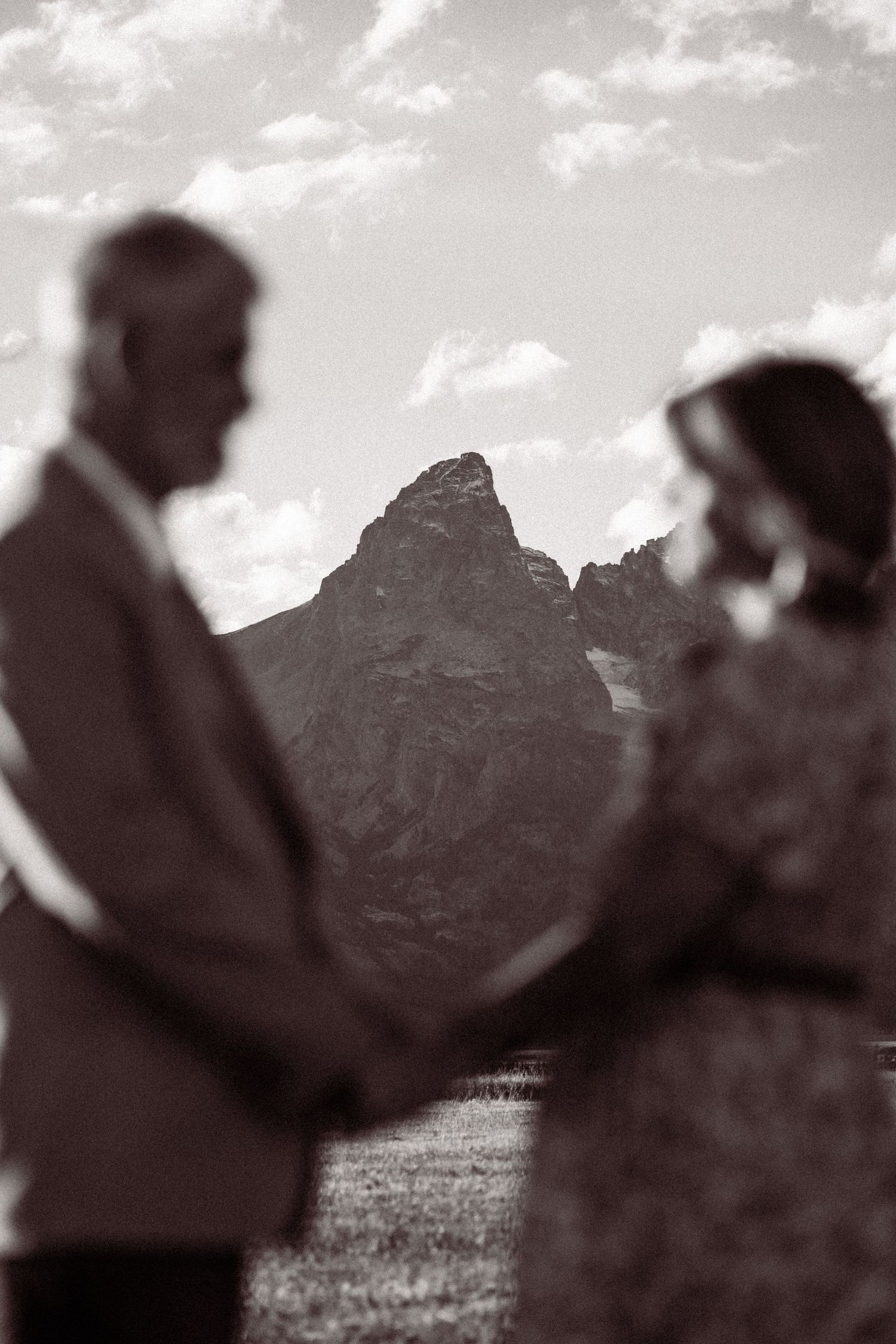 Silhouettes of a couple embracing against a dramatic mountain landscape at dusk.