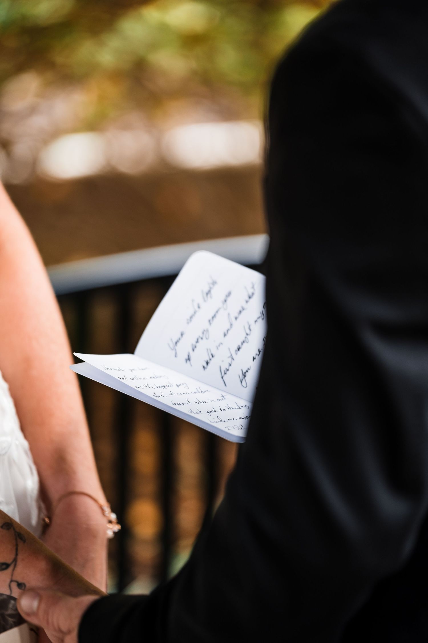 Wedding vows written on paper being held during an outdoor ceremony.