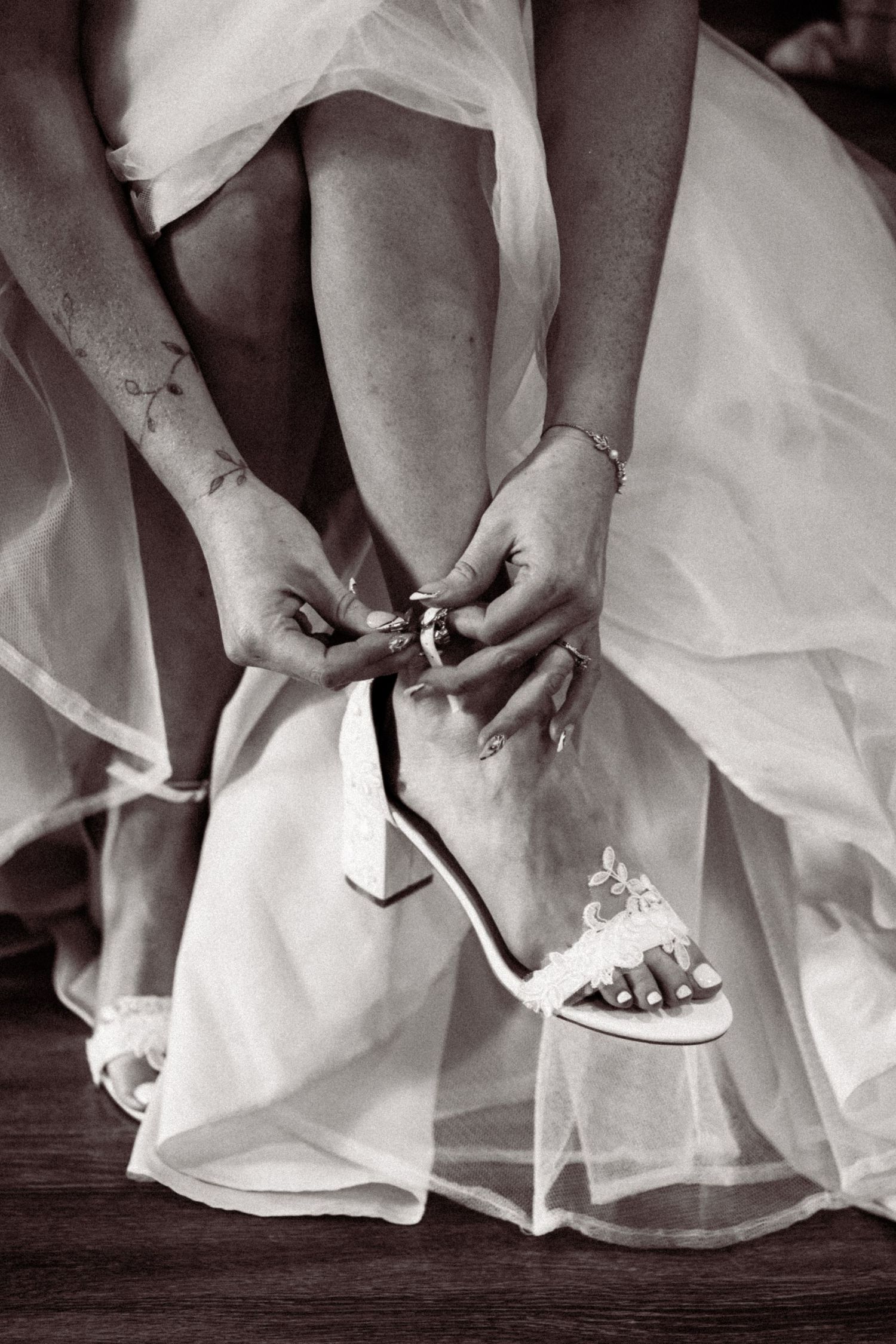 Black and white photo series showing close-up details of a bride adjusting her wedding shoes under her white dress.