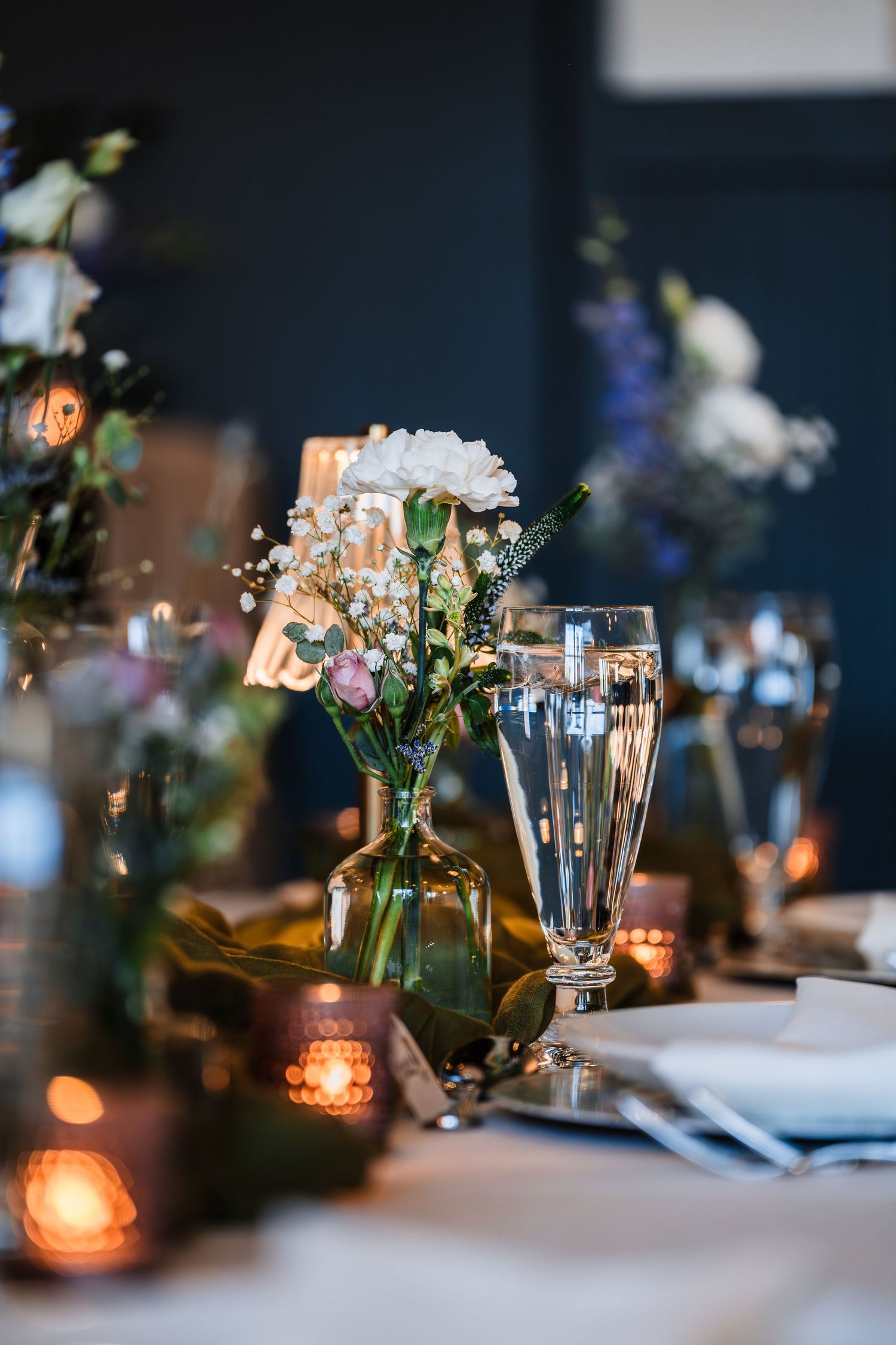 Elegant wedding reception table with floral centerpieces, candles, and crystal glassware.