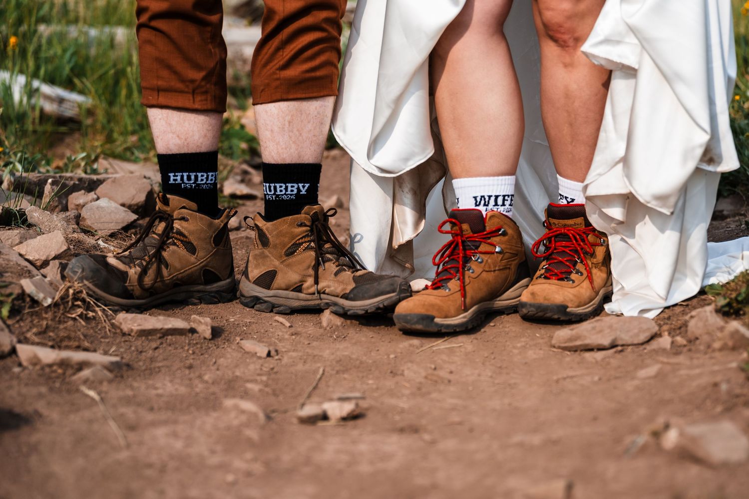 Close-up of wedding couple wearing hubby and wifey socks with hiking boots on dirt trail.