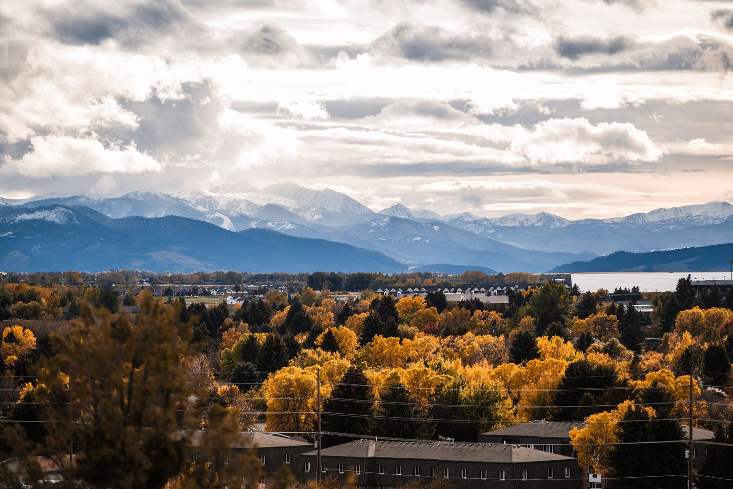 Panoramic mountain landscape view with dramatic cloudy sky and golden autumn trees stretching across multiple frames.