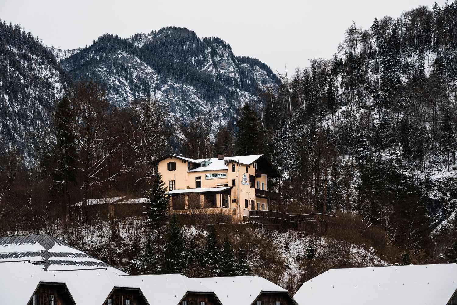 A series of snowy mountain landscape photos featuring a modern house nestled among snow-covered peaks and evergreen trees.