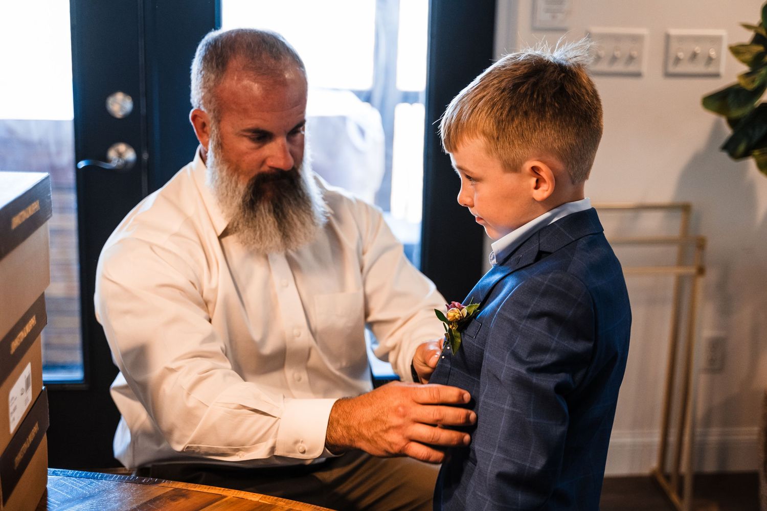 A touching moment between two people during formal dress preparation featuring a navy suit.