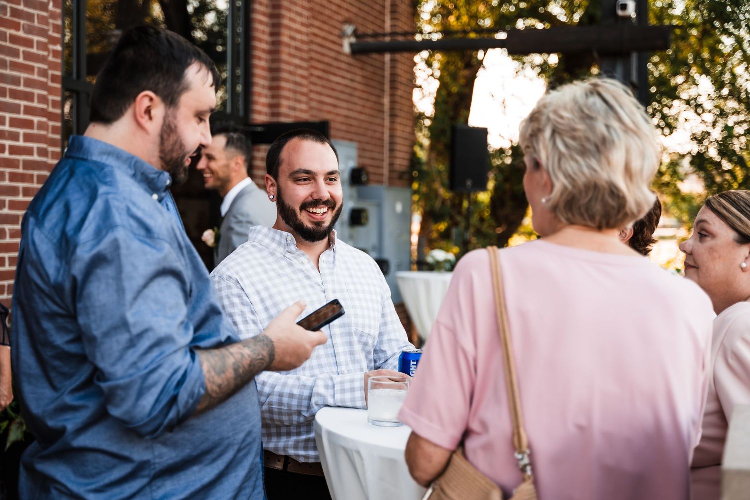 A small group chats and mingles during an outdoor gathering near a brick building.